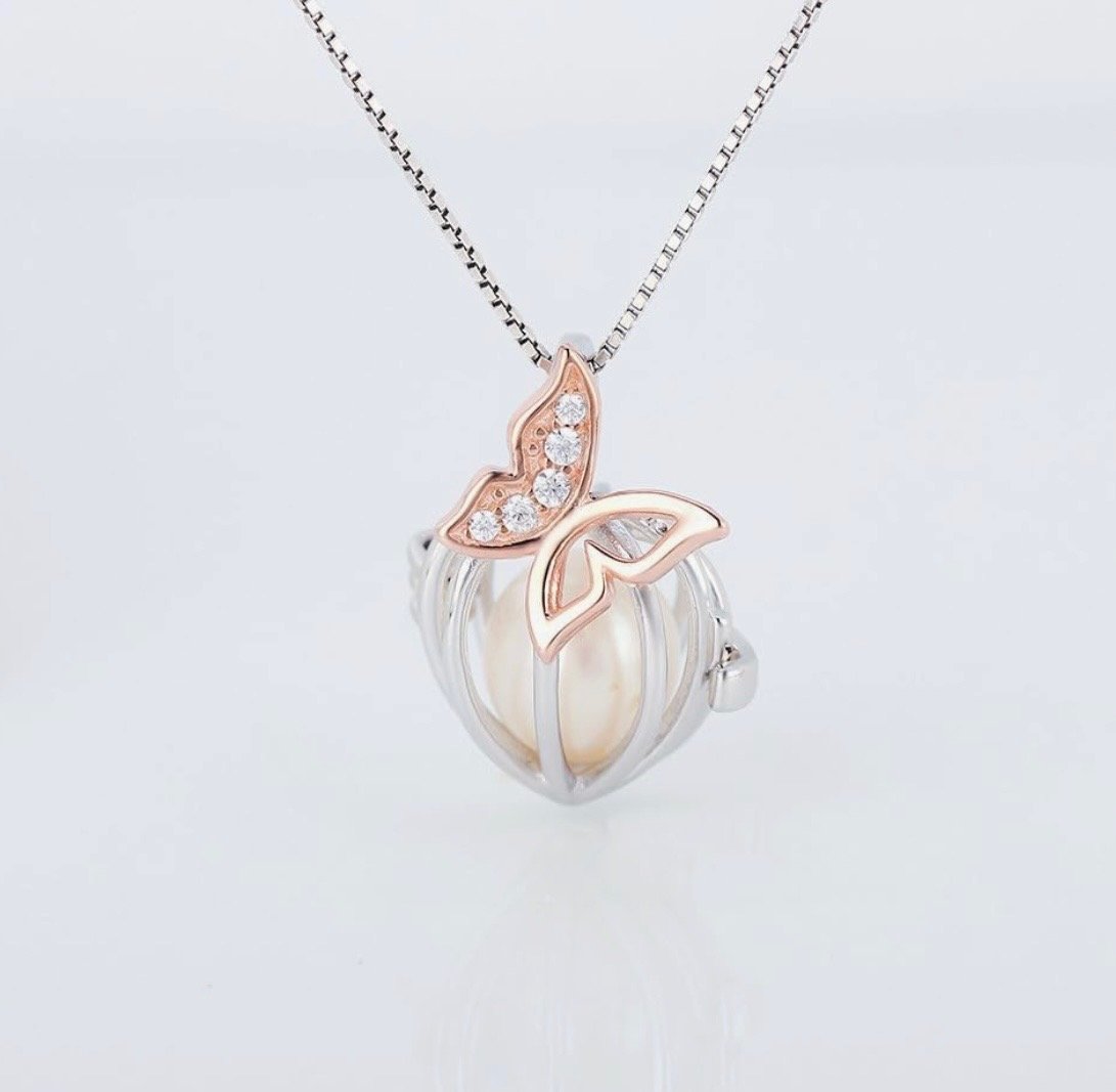 Silver and rose gold necklace with butterfly and leaf charms, featuring a pearl and diamond accents, displayed against a plain light background.