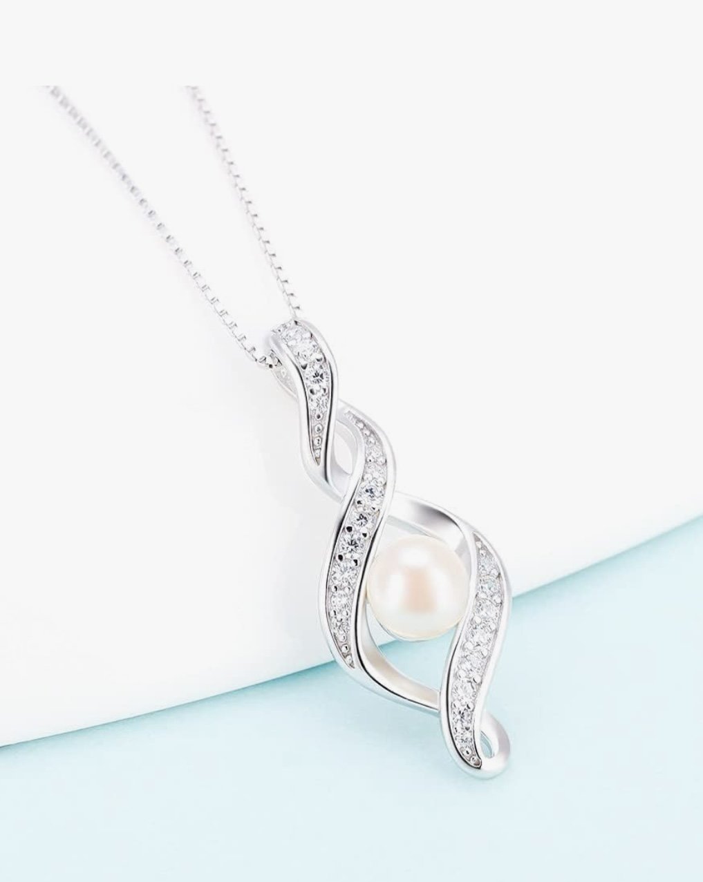 Silver necklace with a swirling design, adorned with diamonds, and a single pearl at the center.