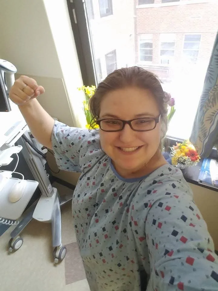 A picture of Jessica Allen in 2017 during a hospital stay that would change her life. She is flexing her right arm in a show of strength.