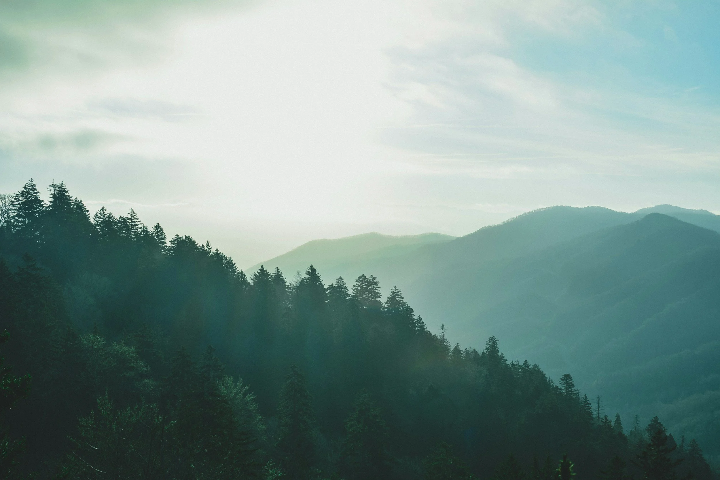 A scenic view of green forested mountains under a cloudy sky.