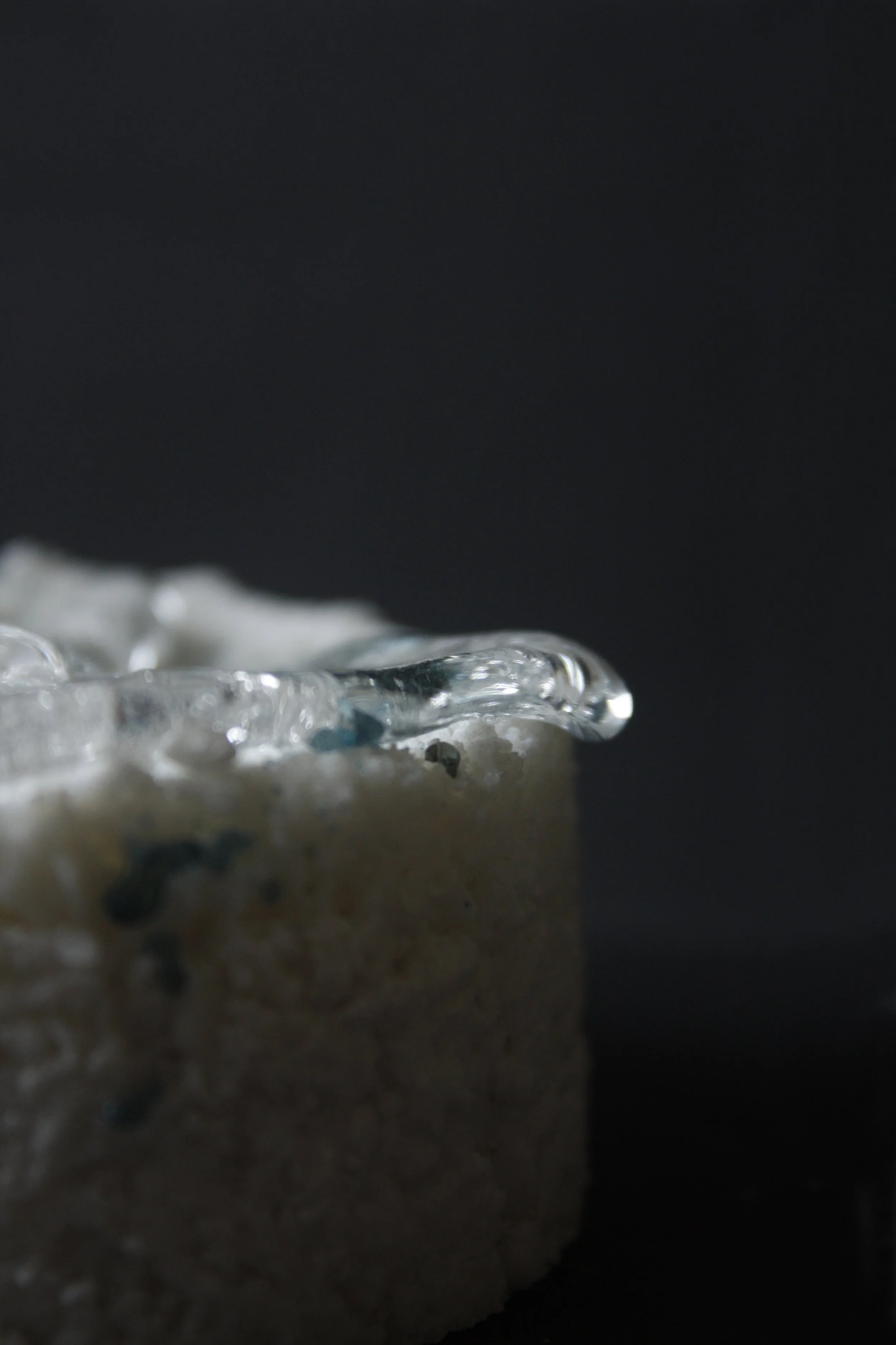 Close-up view of a bread crumb topped with melted cheese and herbs, with a dark background.