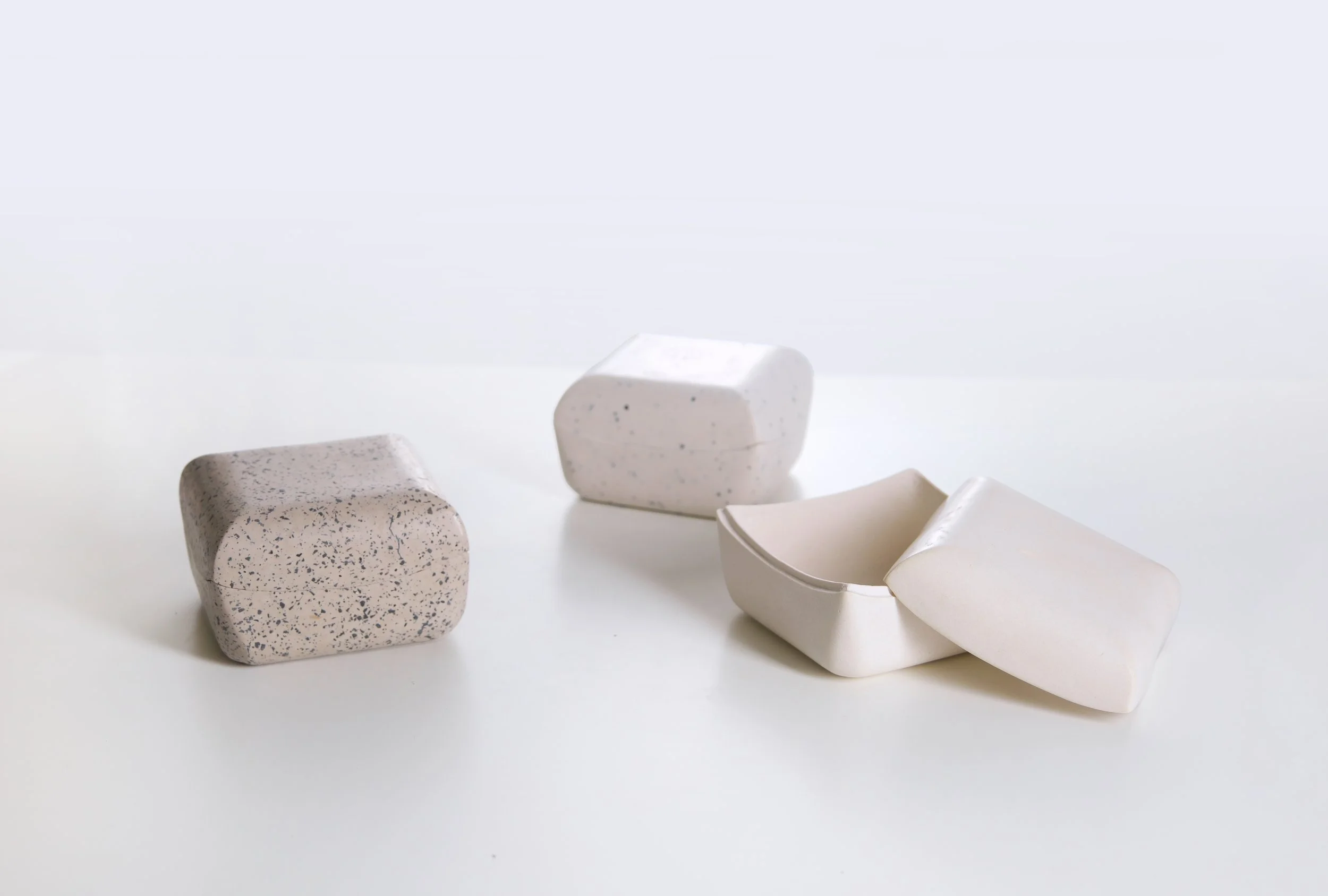 Various pieces of white and speckled soap arranged on a white surface.