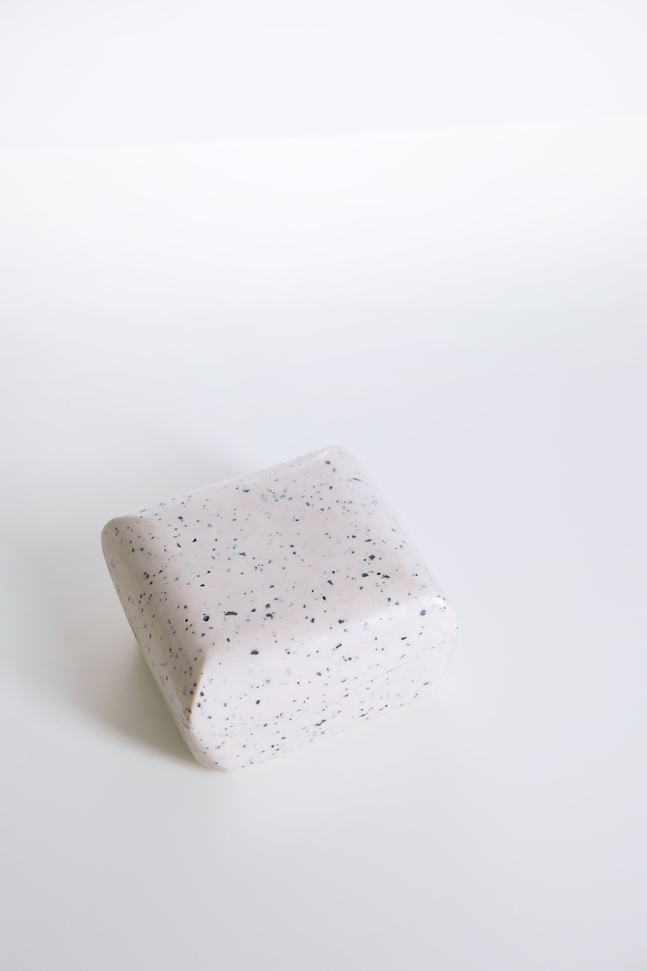 White soap with black speckles on a white background.