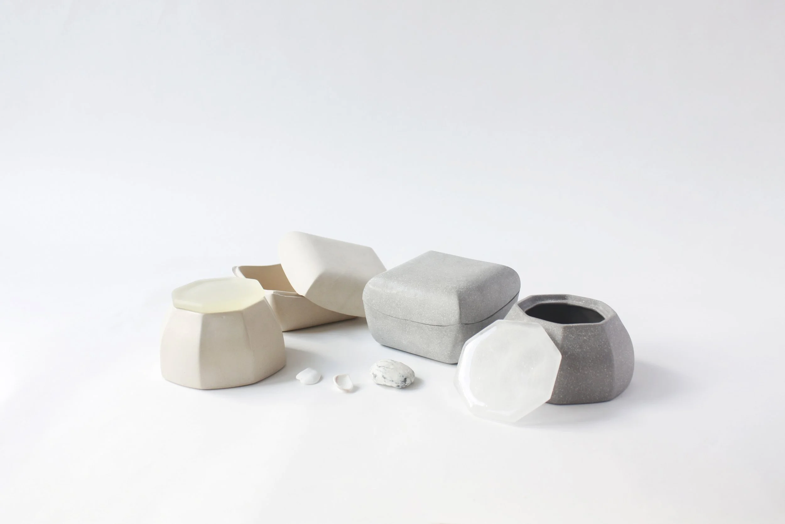 Collection of various assorted stones and ceramic objects in white, gray, and black colors on a white background.