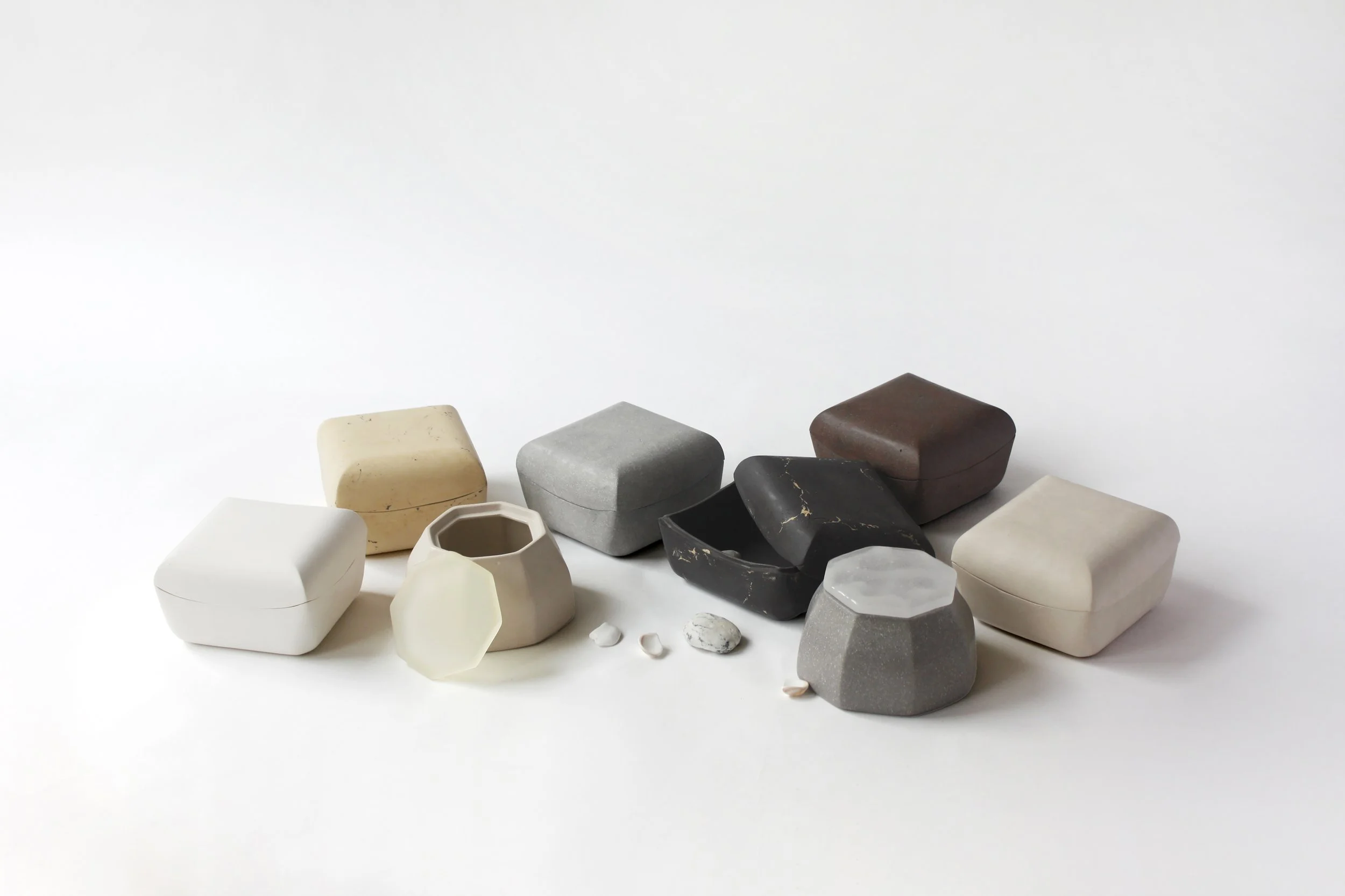 Various stones and ceramic pottery pieces arranged on a white surface and background.