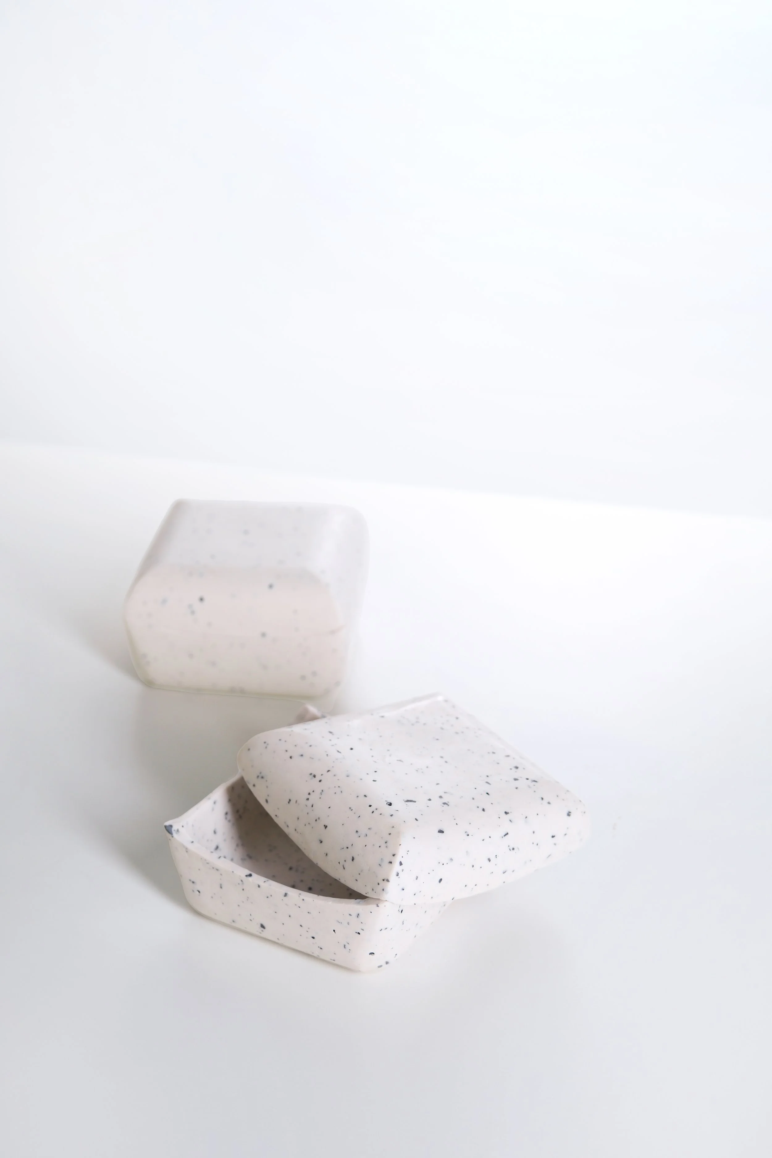 Three pieces of white biodegradable packaging foam with small black speckles on a white surface.