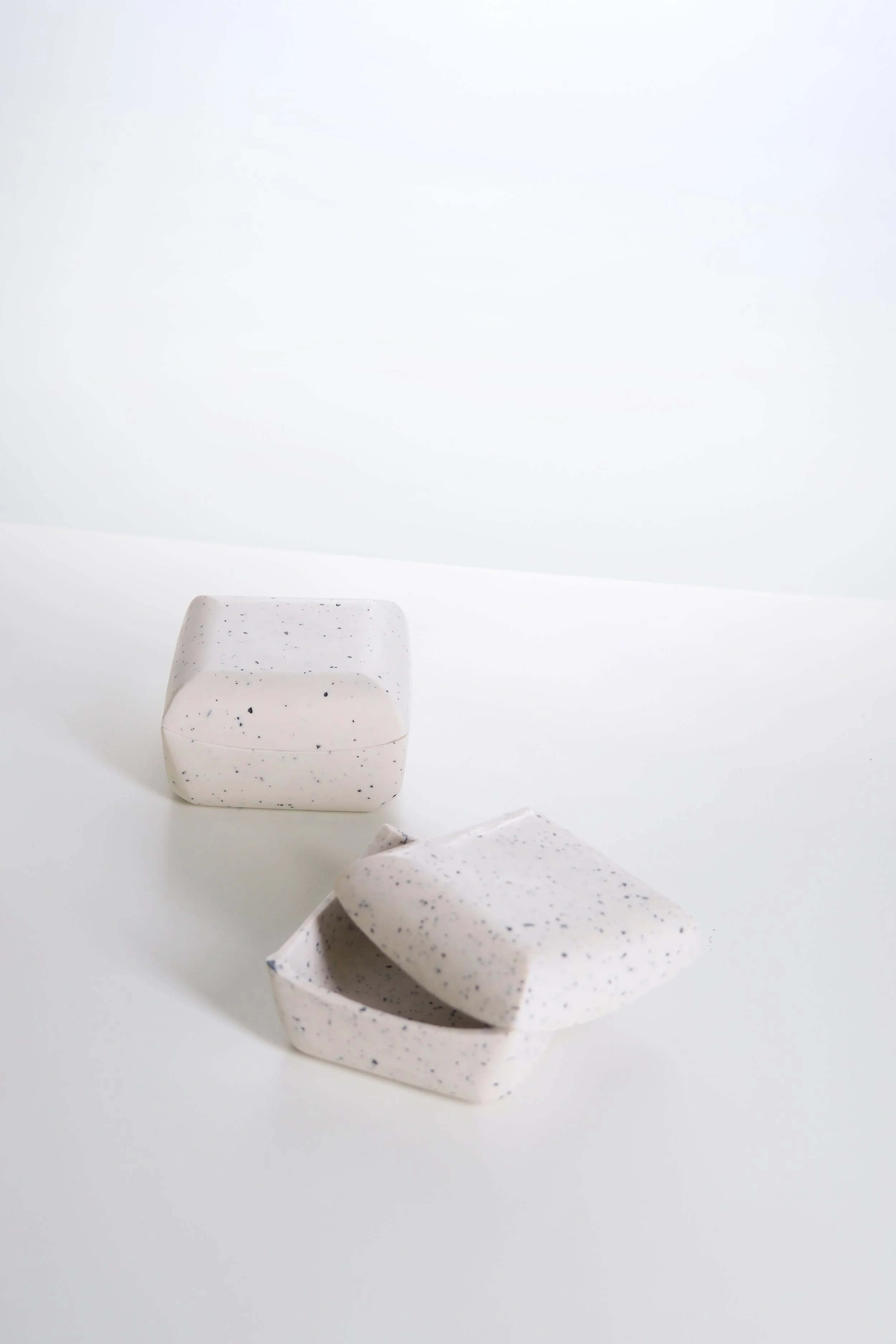 Two white paper fortune tellers with black speckles on a white surface, one partially unfolded and the other closed.
