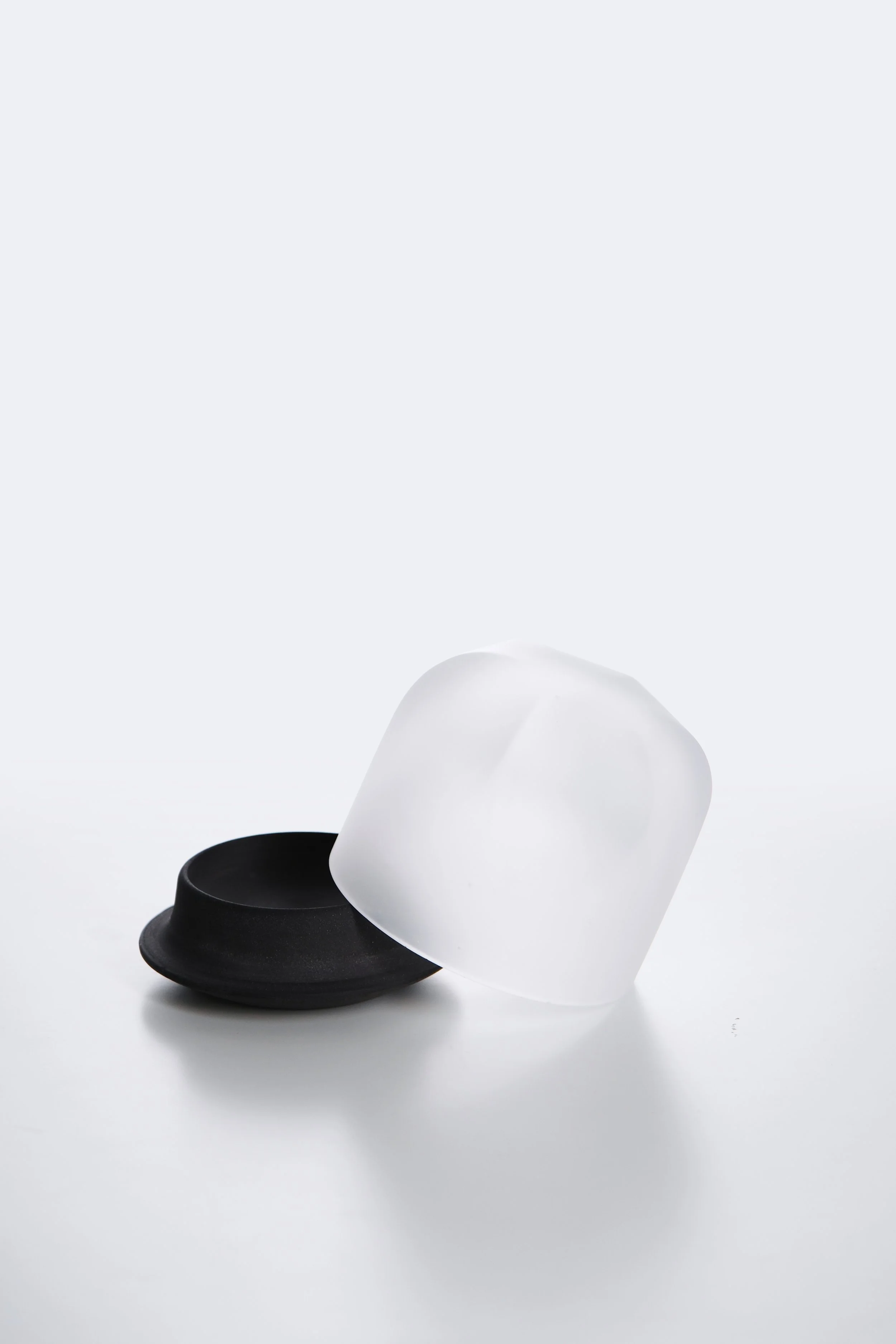 Two minimalist bowls, one black and one white, are stacked on each other against a clean, white background.