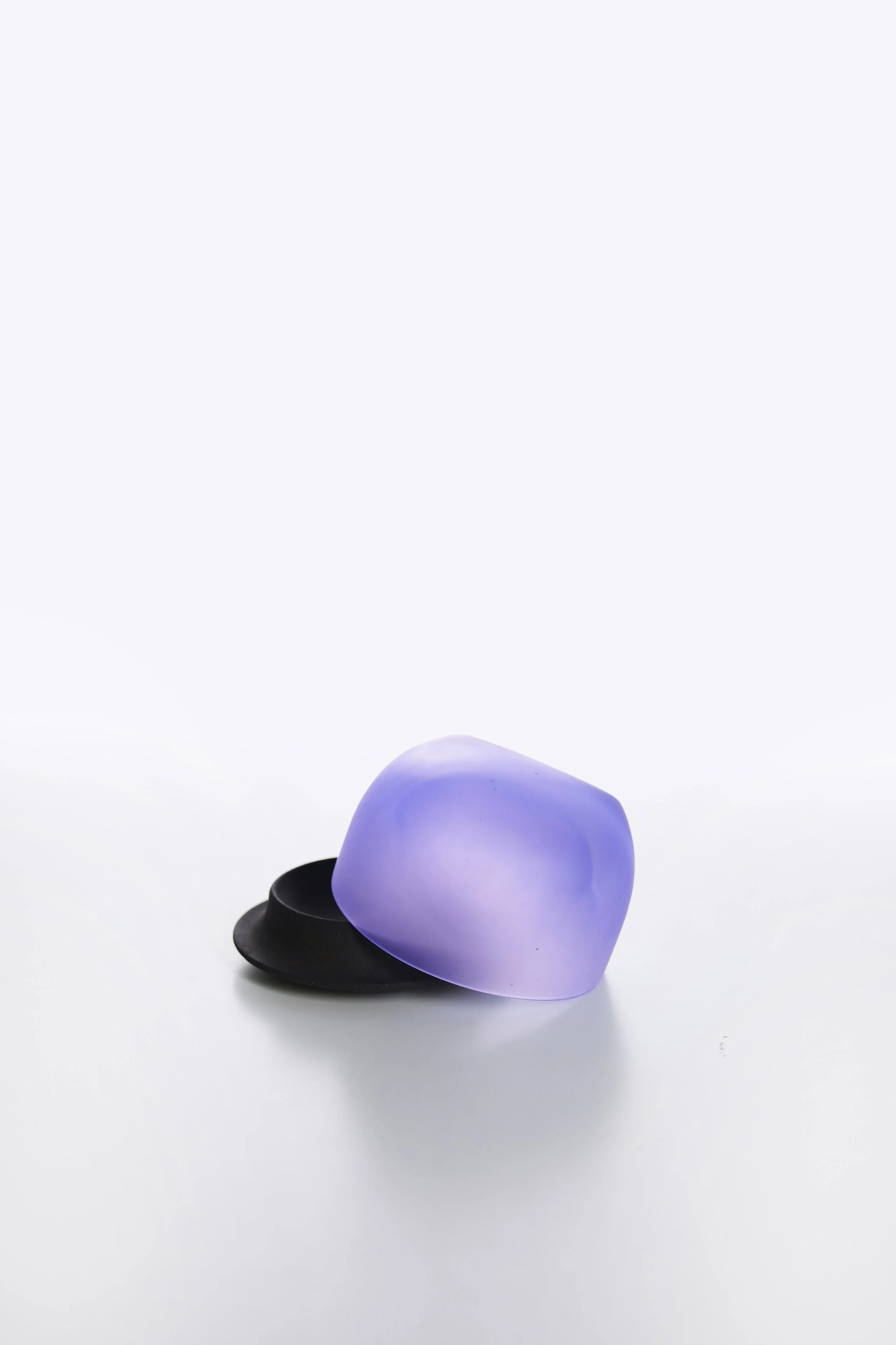 A purple heart-shaped object with a smooth surface, resting on a black dish, against a white background.
