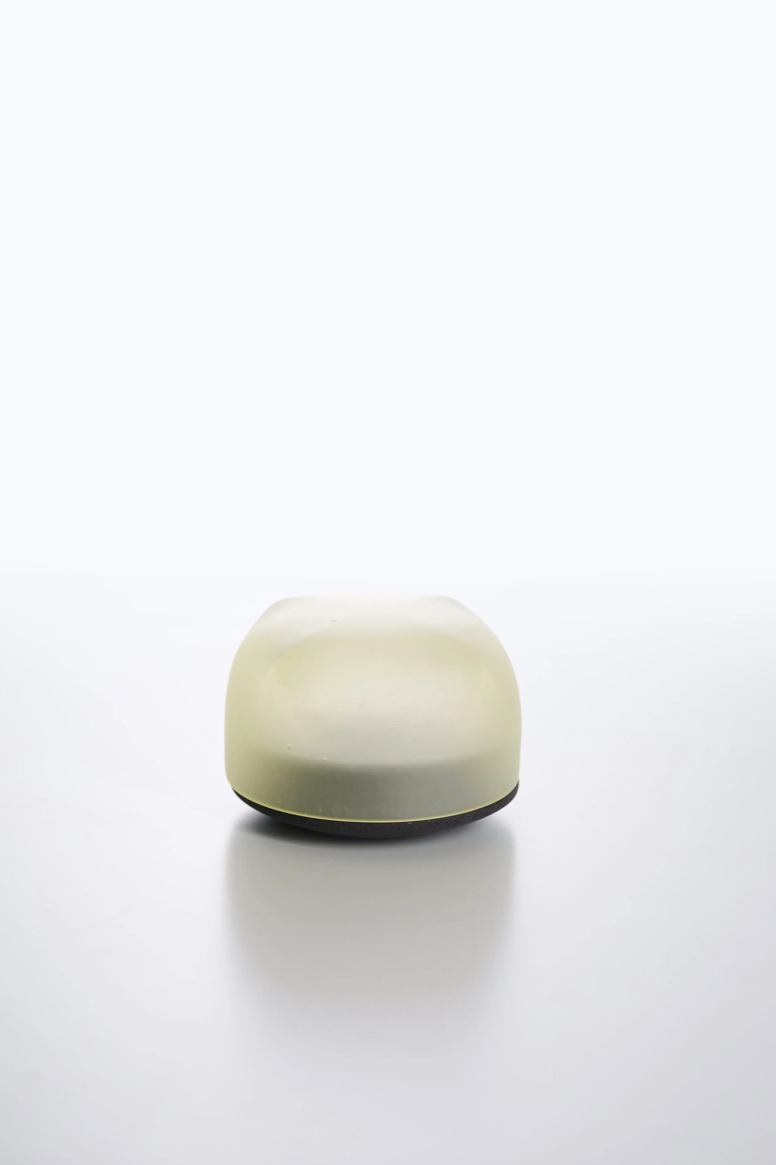 A white and black Apple HomePod mini smart speaker on a white surface with a plain white background.
