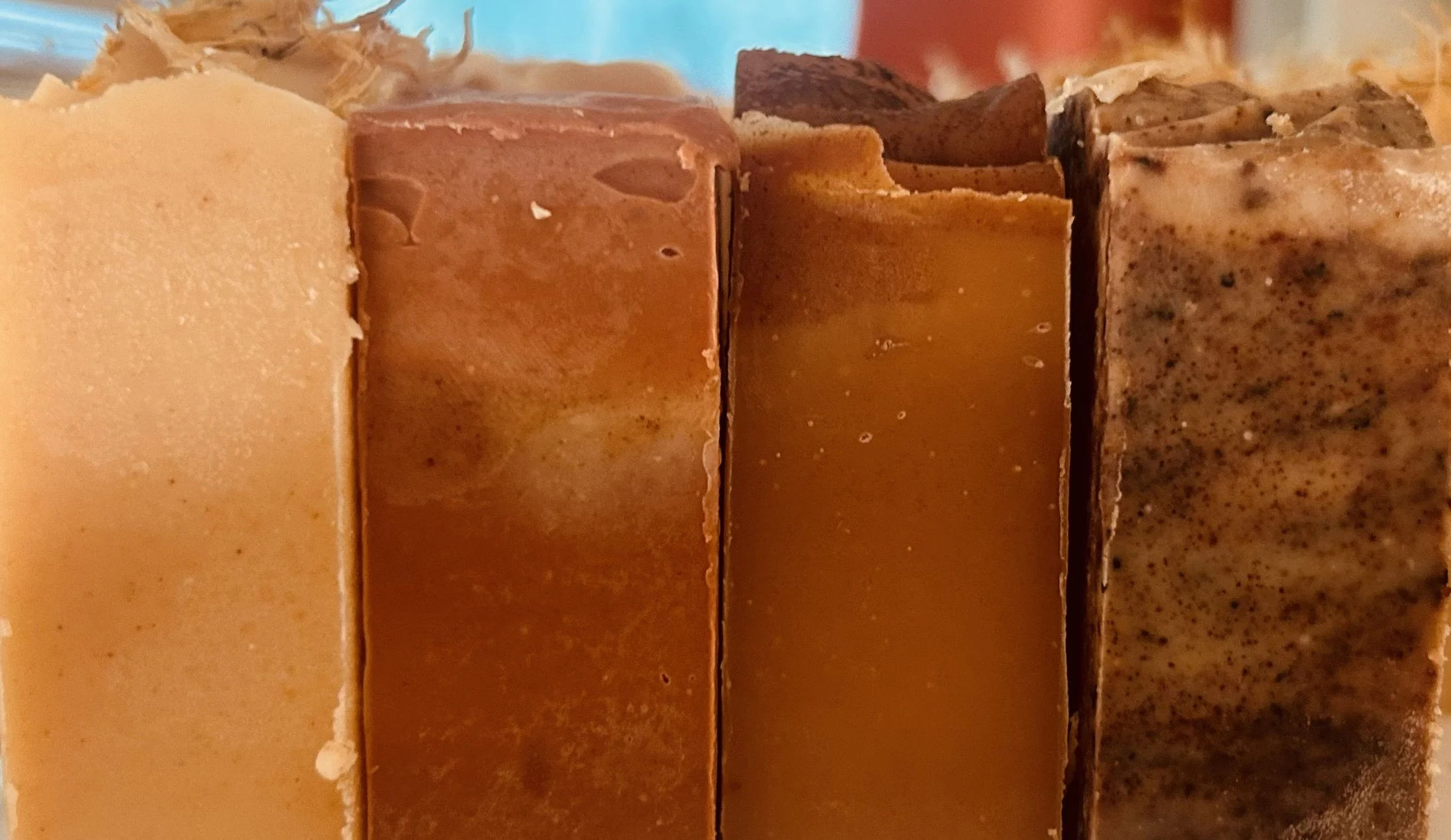 Close-up of five different types of Skipwillow Farm handmade soap bars in various shades of brown and beige stacked vertically.