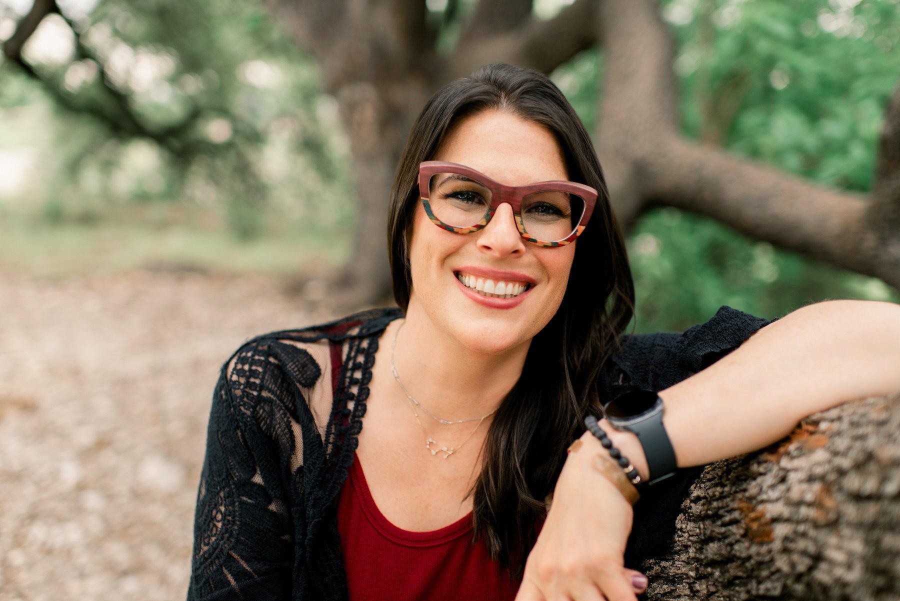 Learn about Joann Chevaillier off the clock, she leans her arm against a tree branch and smiles outside.