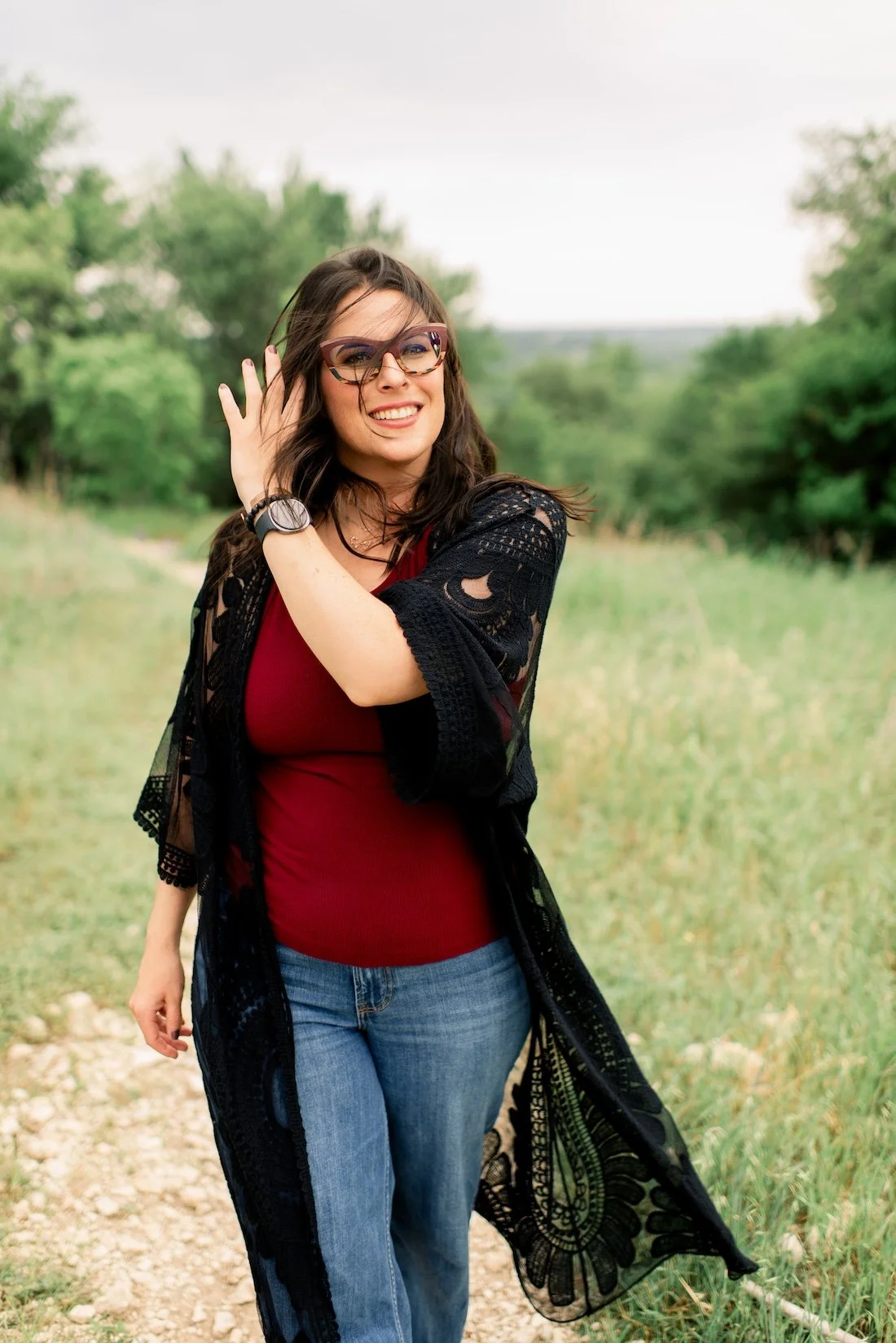 Joann Chevaillier, LPC-Associate, smiling outdoors during a Walk & Talk Therapy session in Fort Worth, Texas, walking on a grassy path with trees in the background.