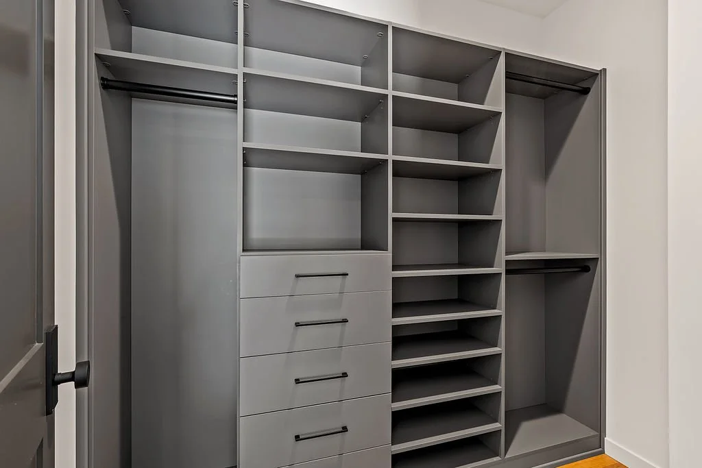Empty walk-in closet with gray shelving, drawers, and hanging rods.