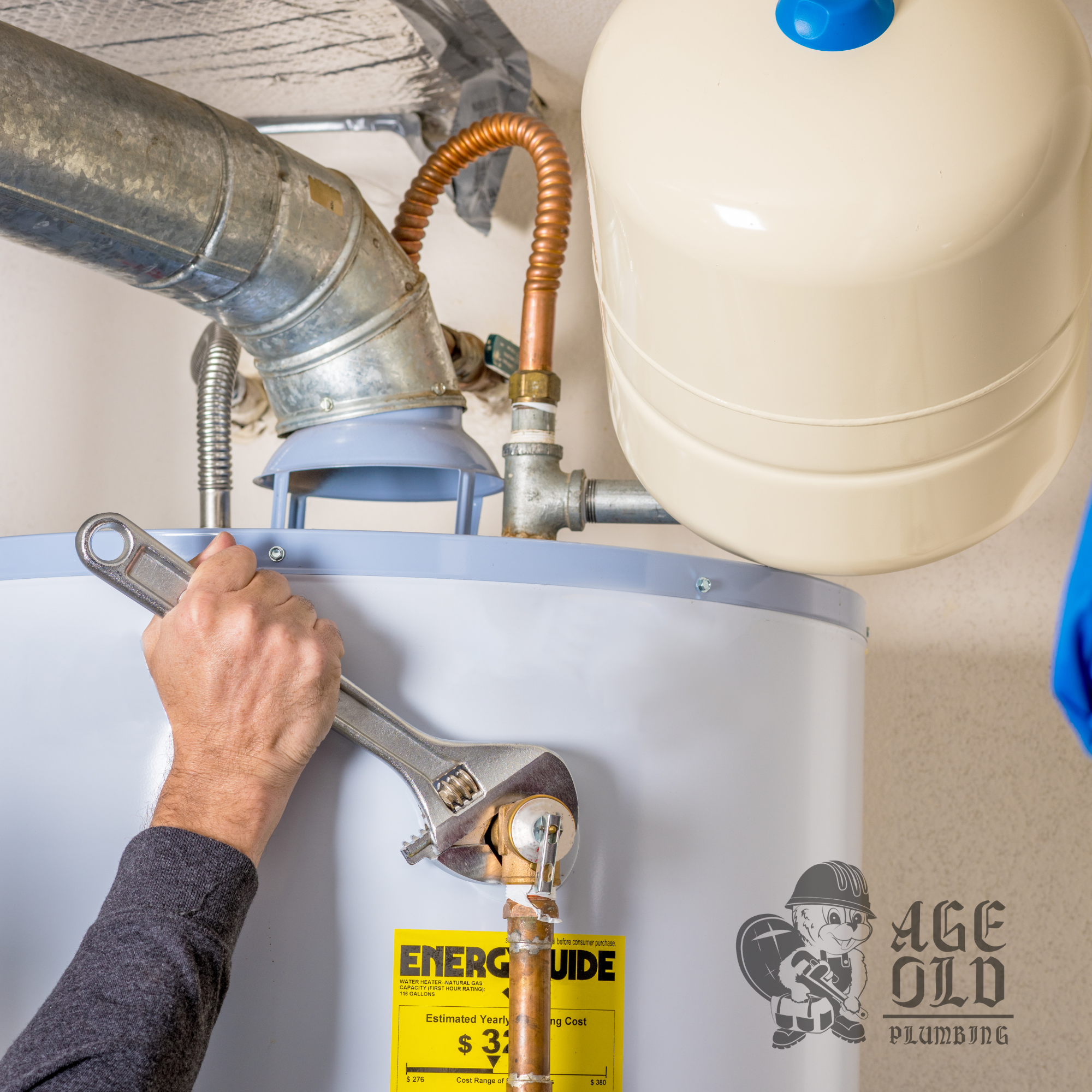 Person wearing a gray long-sleeve shirt adjusting a gas pipe connected to a water heater. The water heater has a yellow energy guide label and appears installed indoors.