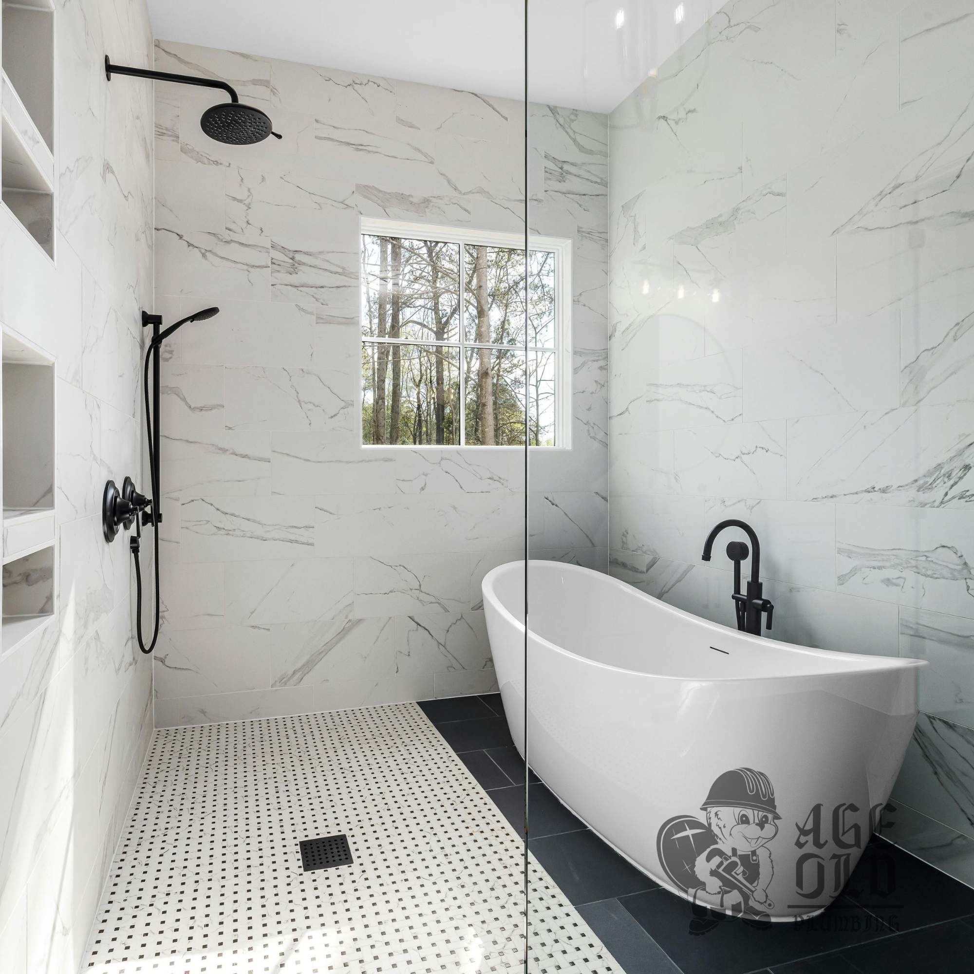 Modern bathroom shower area with black shower fixtures, white marble walls, a window showing trees outside, black and white mosaic tile flooring, and a freestanding bathtub.