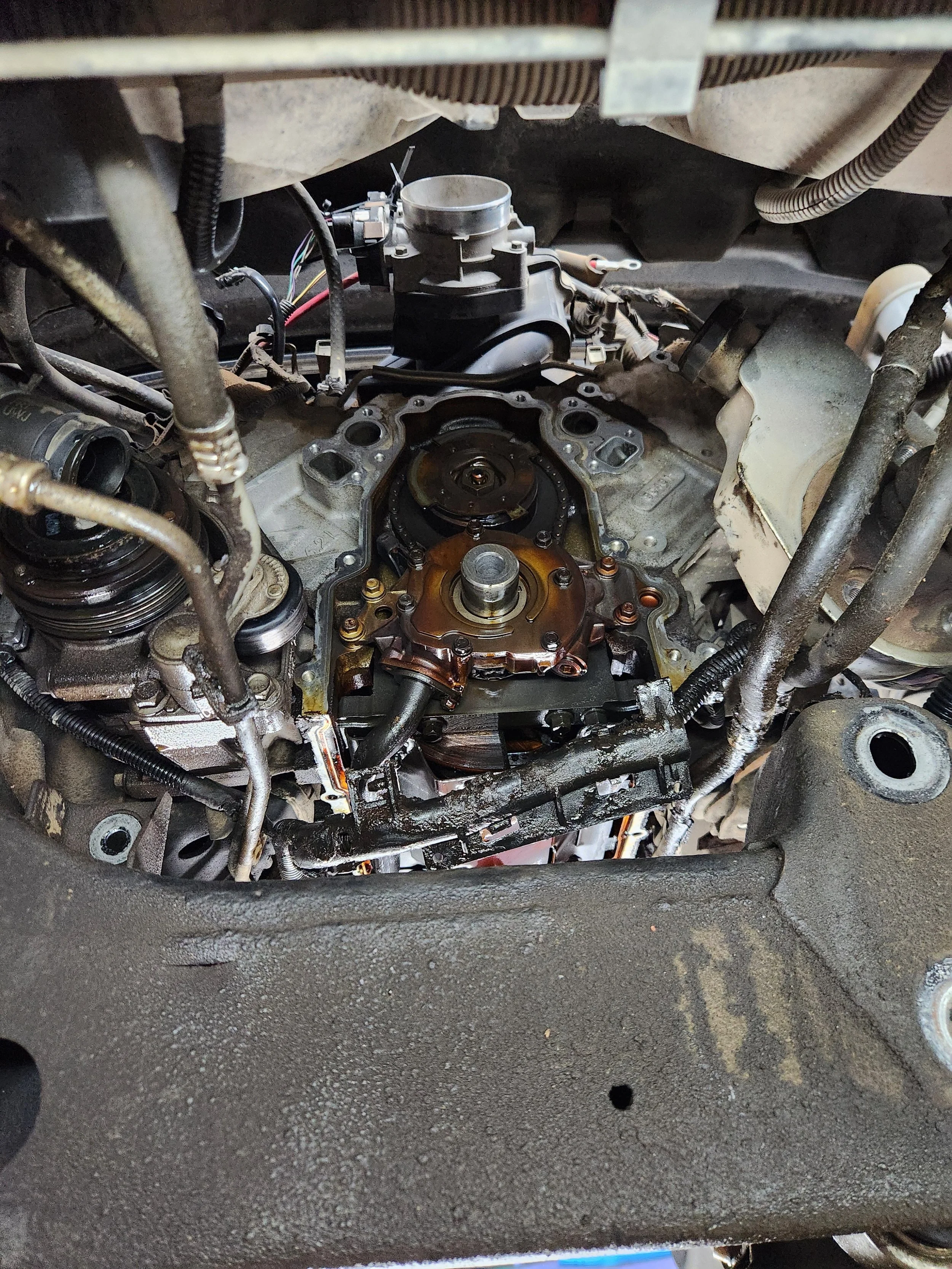 Close-up of a disassembled car engine showing various mechanical parts, wires, and oil.
