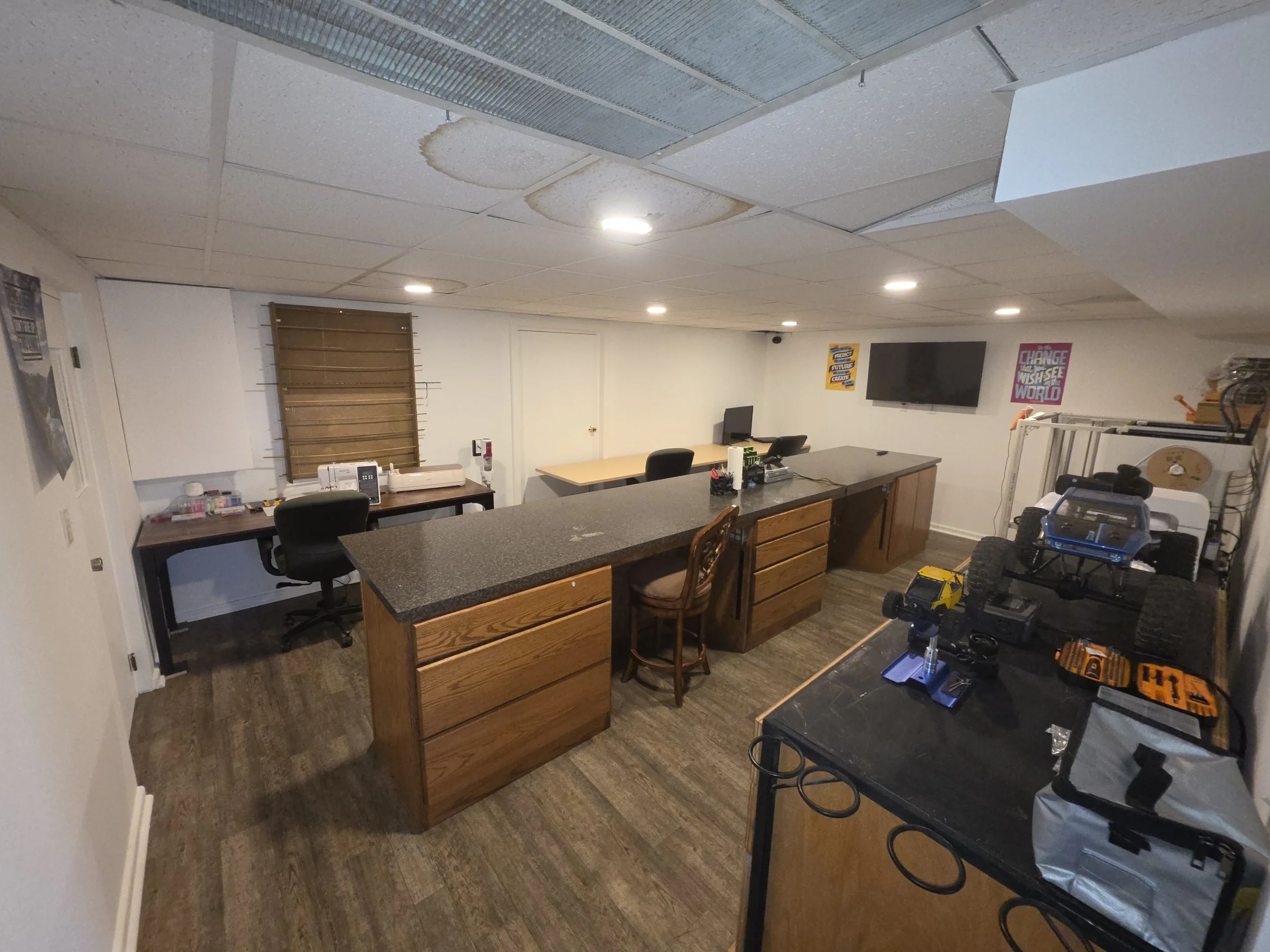 Maker room with lights, a sewing machine, 3D Printers, t-shirt press, RC cars, and large work surface.