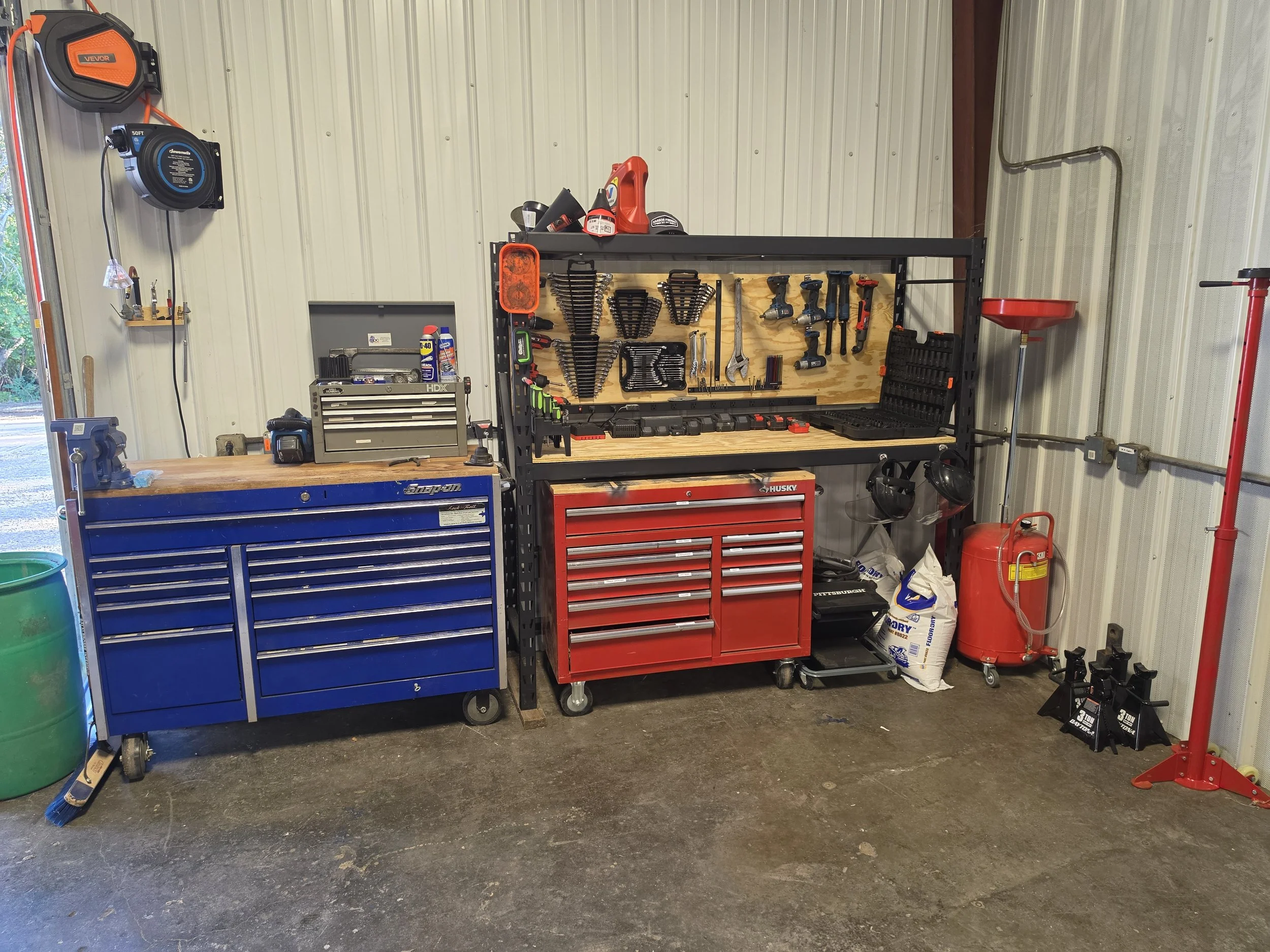 A well-organized garage workshop with a blue and red tool chest, pegboard with tools, a workbench, and various garage equipment and safety gear.