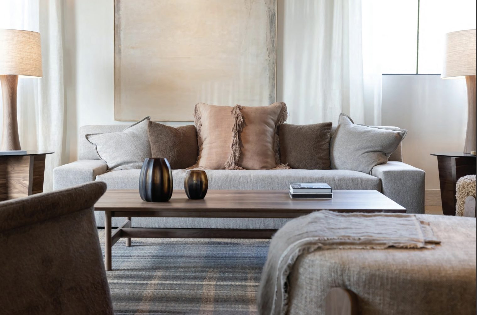 Living room with beige sofa, decorative pillows, wooden coffee table, and lamps with beige shades
