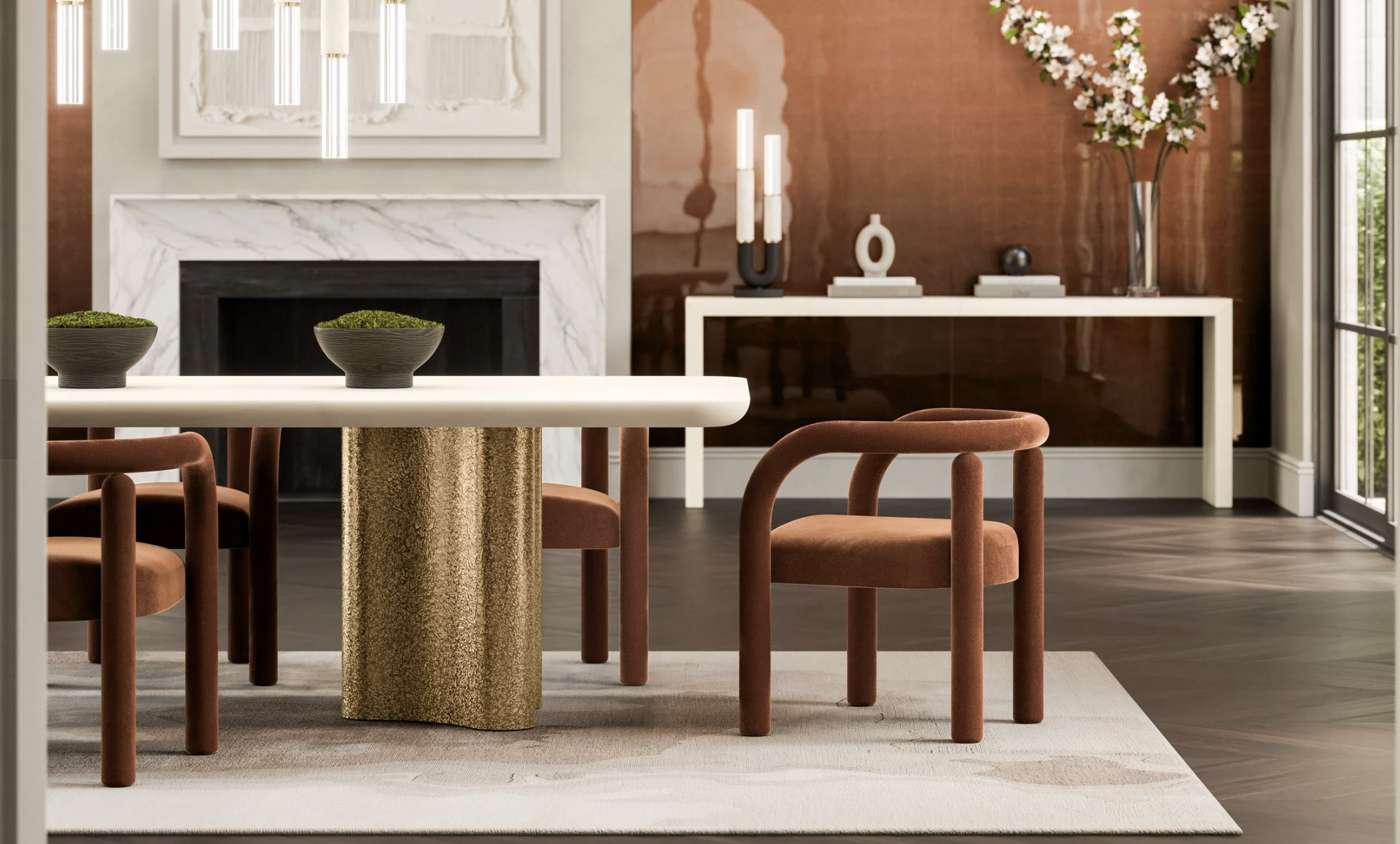 Modern living room with a white fireplace, abstract artwork, decorative vases, and a large flower arrangement on a side table. A white and gold table with two bowls of moss, rust-colored chairs with rounded backs, and large windows allowing natural light.