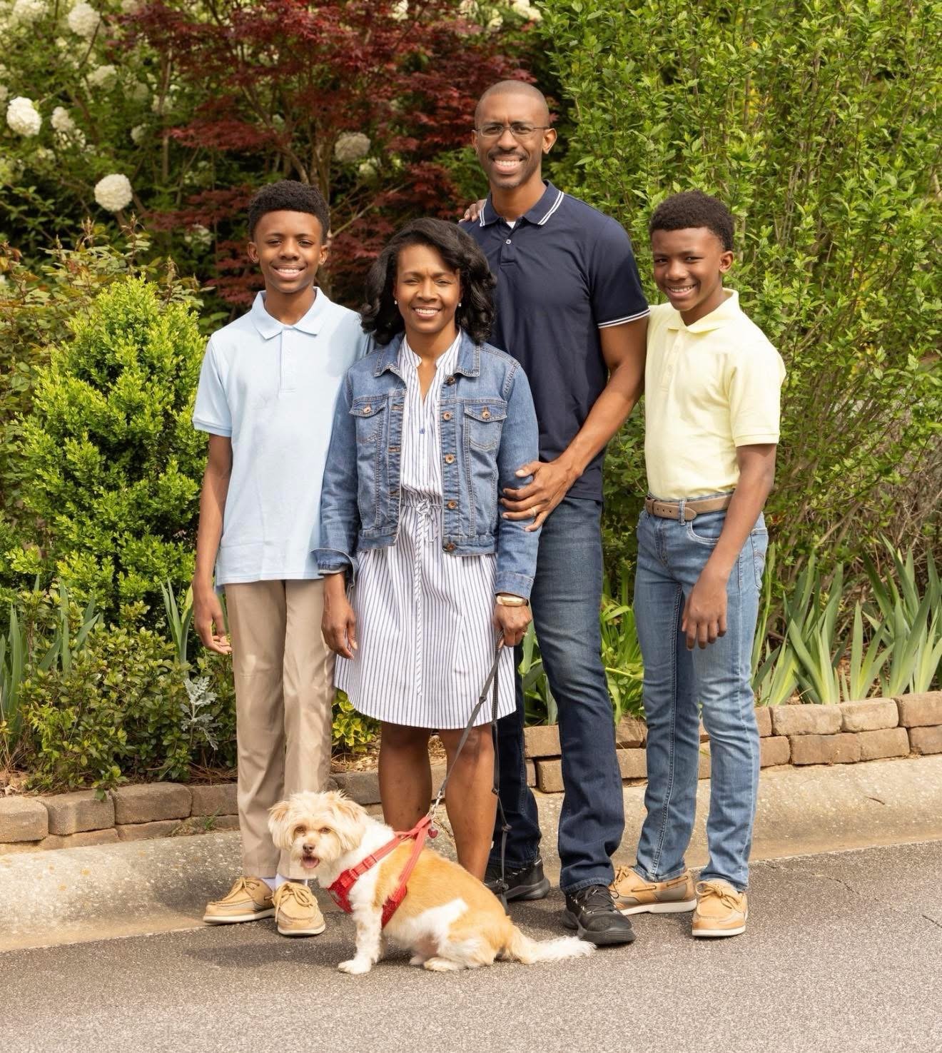 Craig Cupid with his wife Lisa, their two sons, and their small dog with green and red trees in the background
