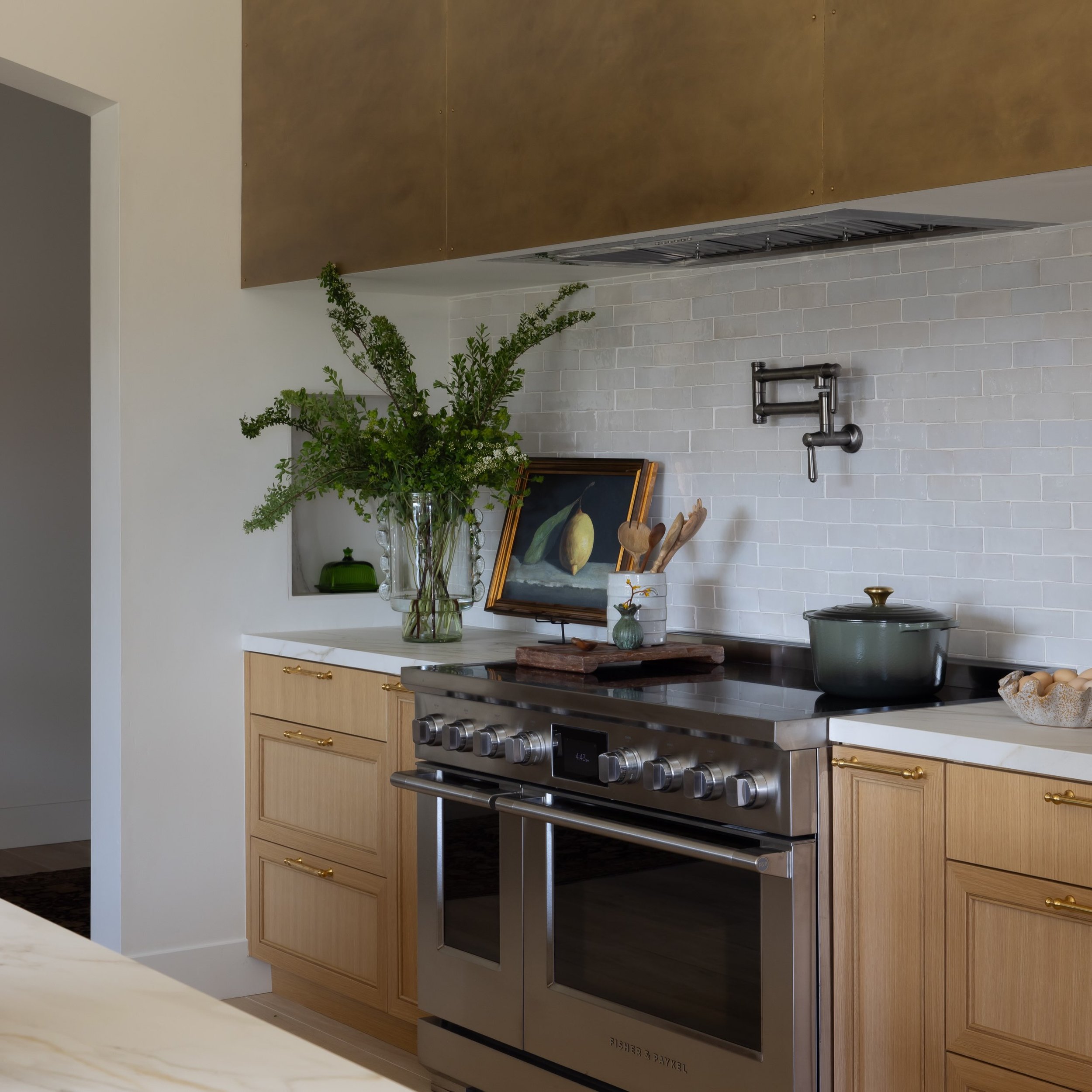 Framed by a pair of arches, this Spanish-inspired kitchen is anchored around an oversized island made for gathering. Every view through the space feels intentional, with a sculptural custom brass hood that quietly steals the show.

Interiors: @vivode