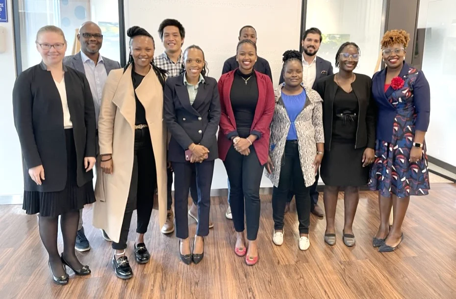 Group photo of 11 men and women from the US and Africa standing in an office on a wood floor