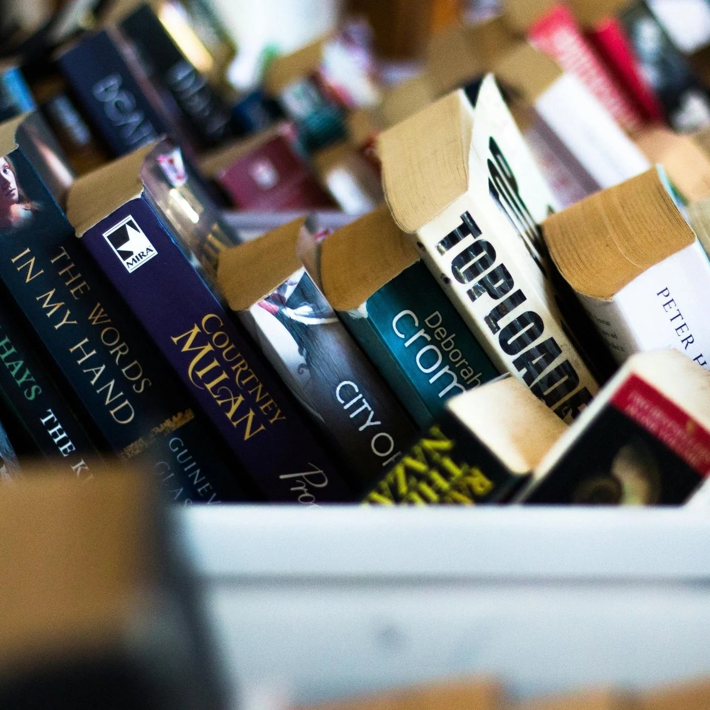 A bin of used paperback books is ready for the Third Thursday book swap at Paper Boat Booksellers