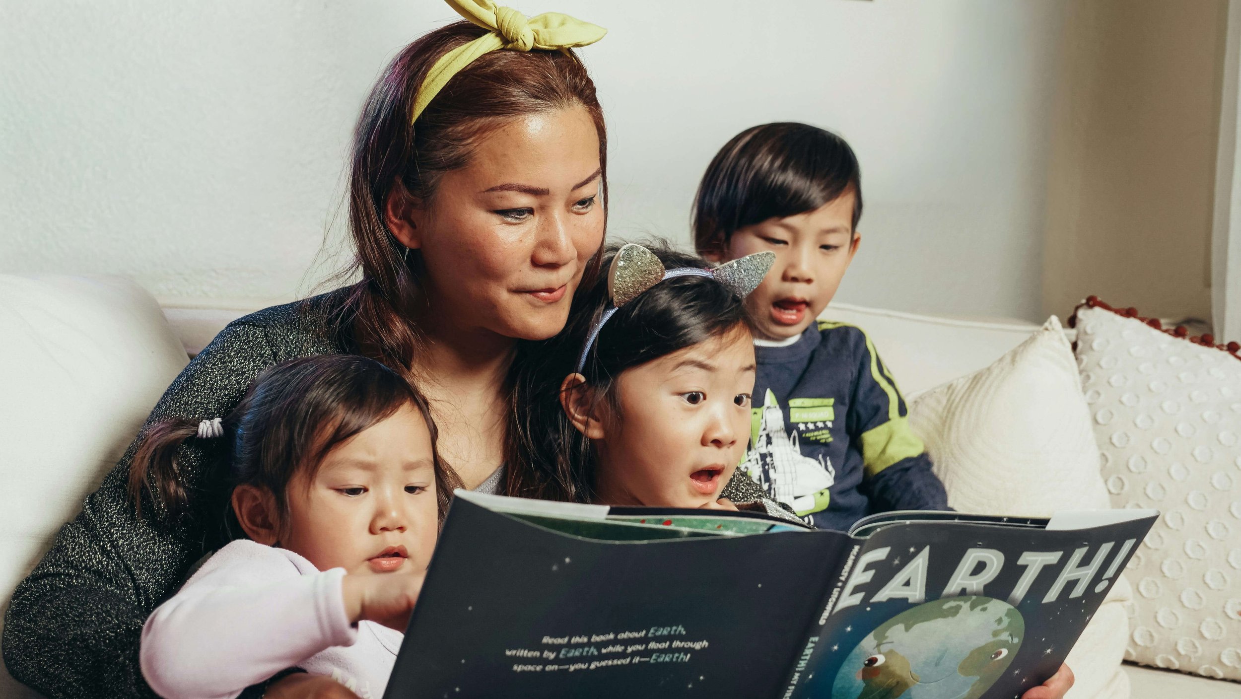 A parent reading a picture book to three young children during Family Reading Time at Paper Boat Booksellers in West Seattle, a free weekly event held Saturday mornings at the independent bookstore