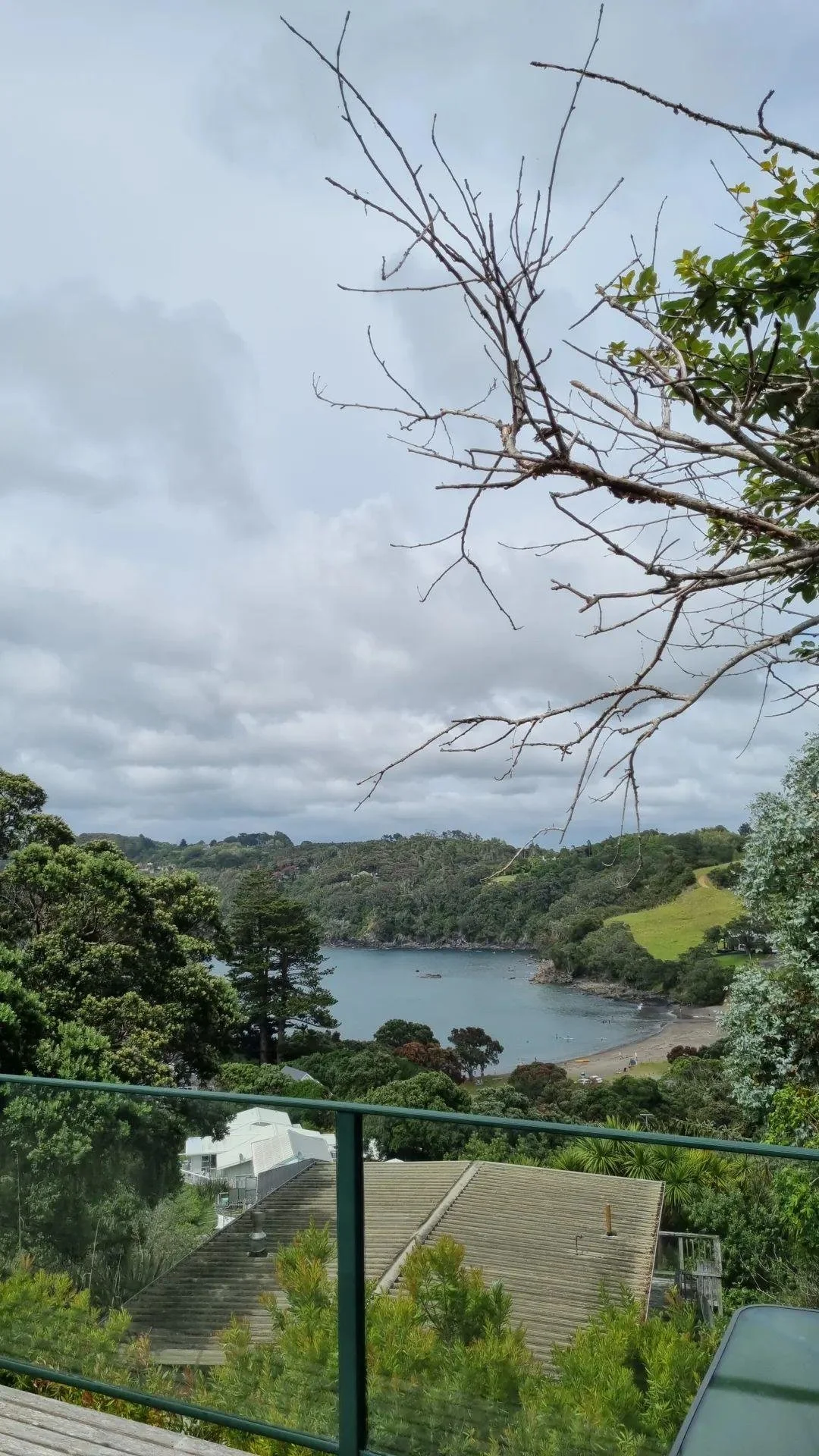 Scenic view of a lake surrounded by green hills and trees, with a cloudy sky overhead.