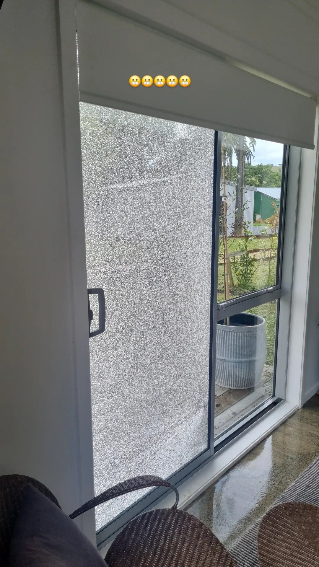 Sliding glass door with frosted privacy film partially open, revealing a view of a garden with plants and a large planter outside.