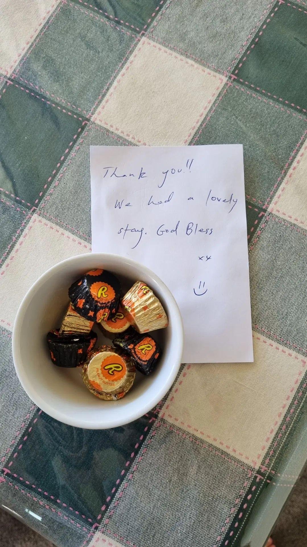 A bowl with Halloween themed chocolates on a table with a handwritten thank you note.