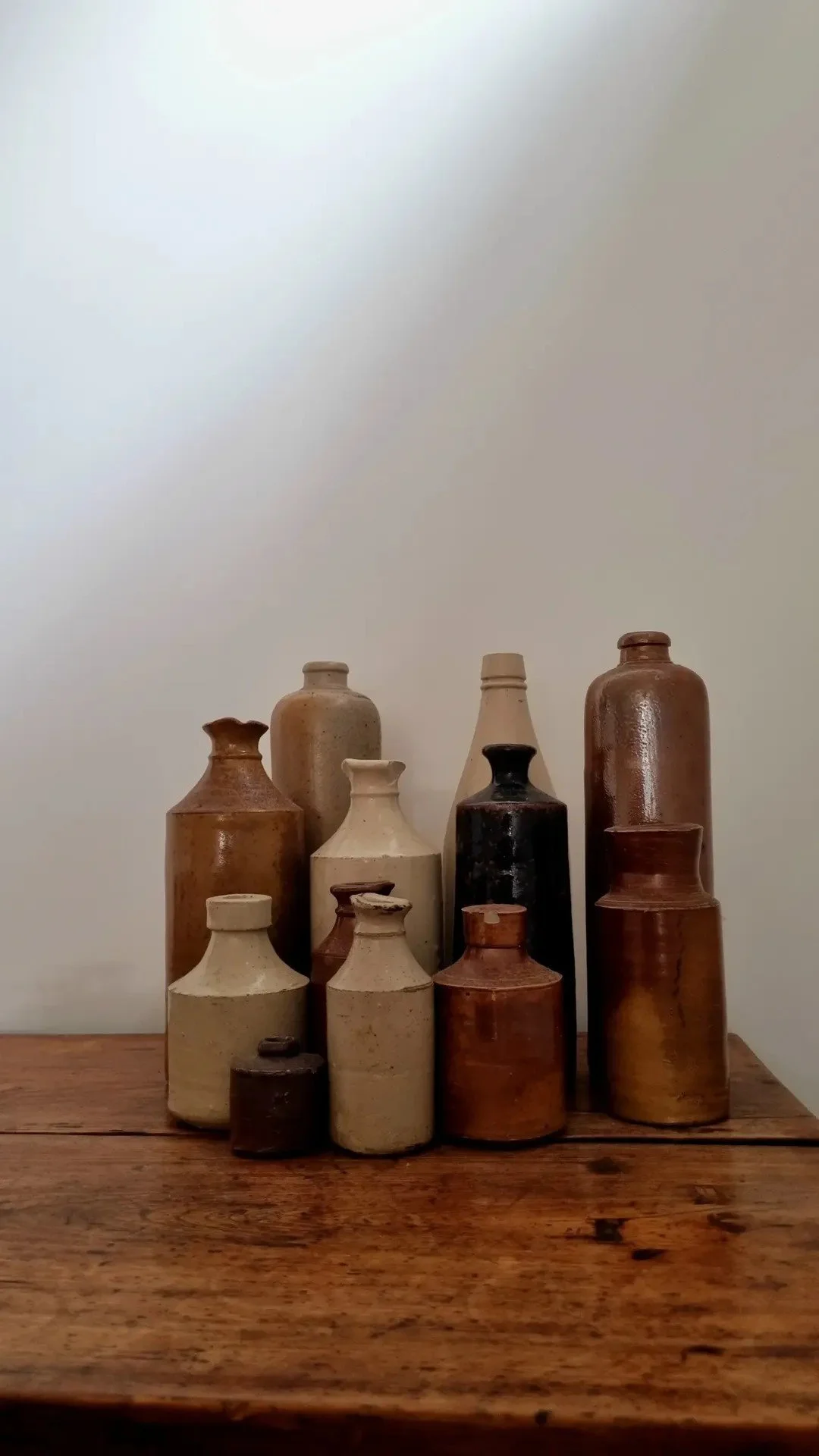 Collection of various ceramic and pottery vases on a wooden surface.