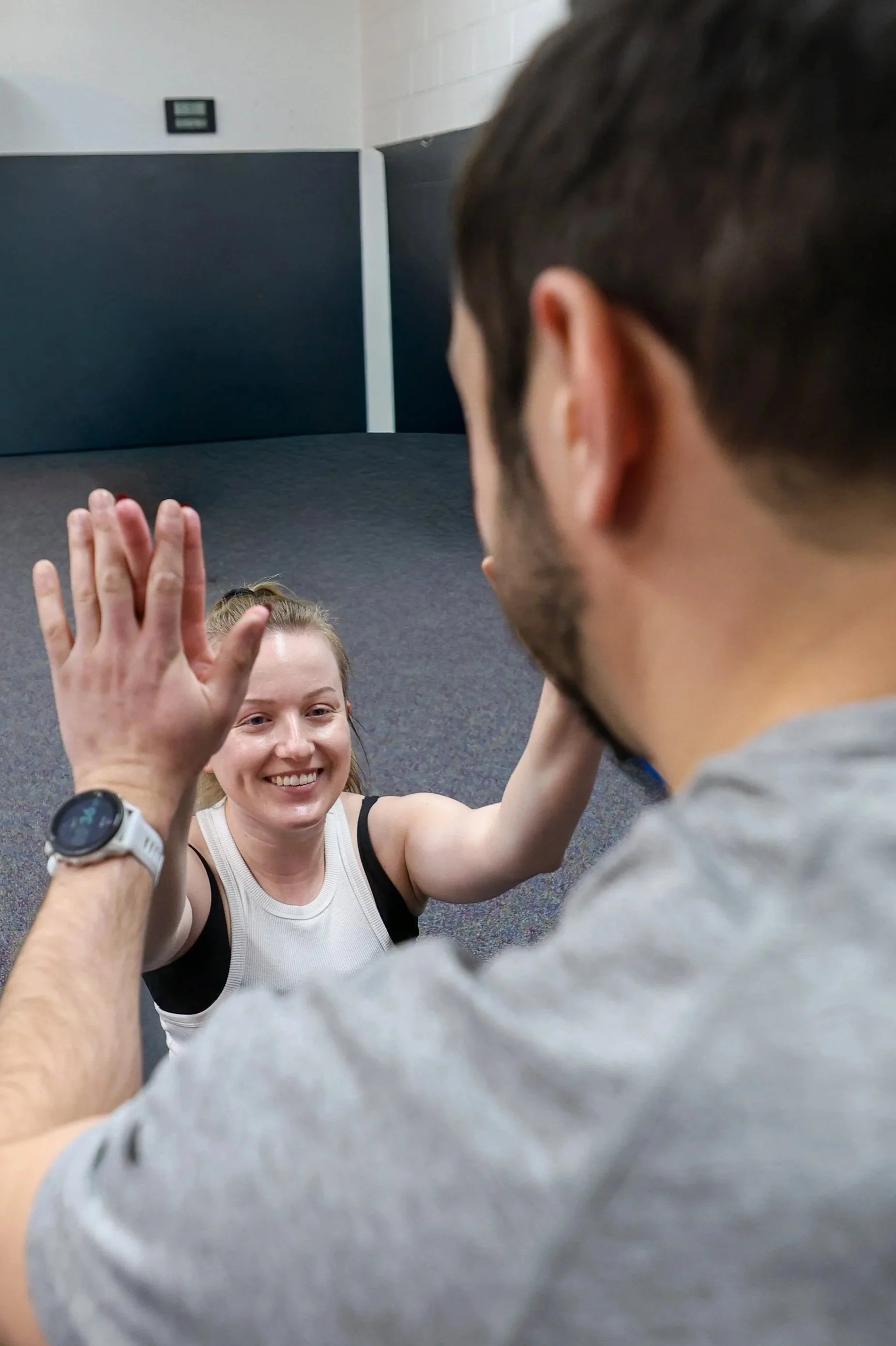 women smiling as she completes a situp and high fiving the coach ensuring full range of motion