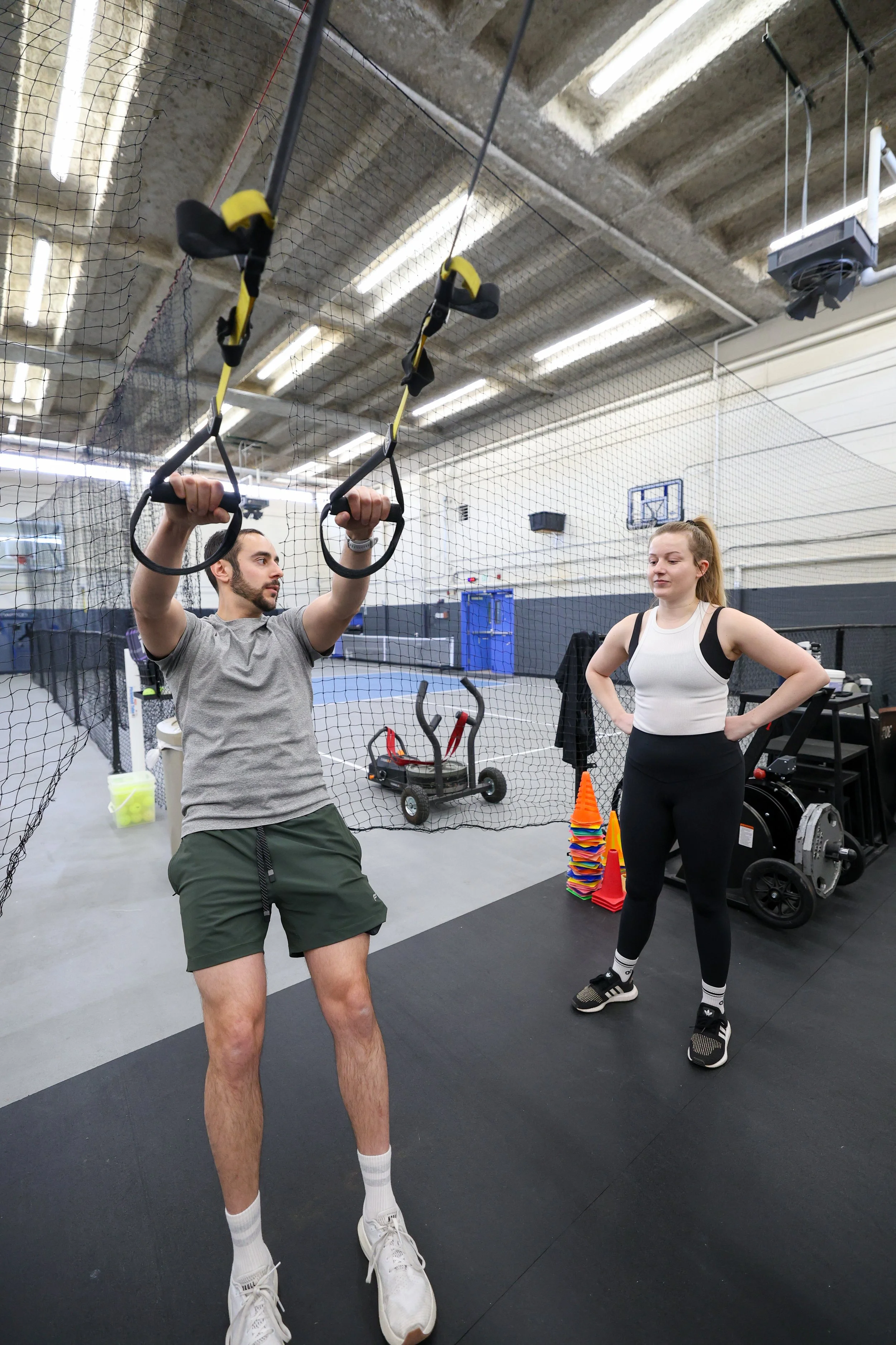 coach demonstrating a trx high pull row for a client