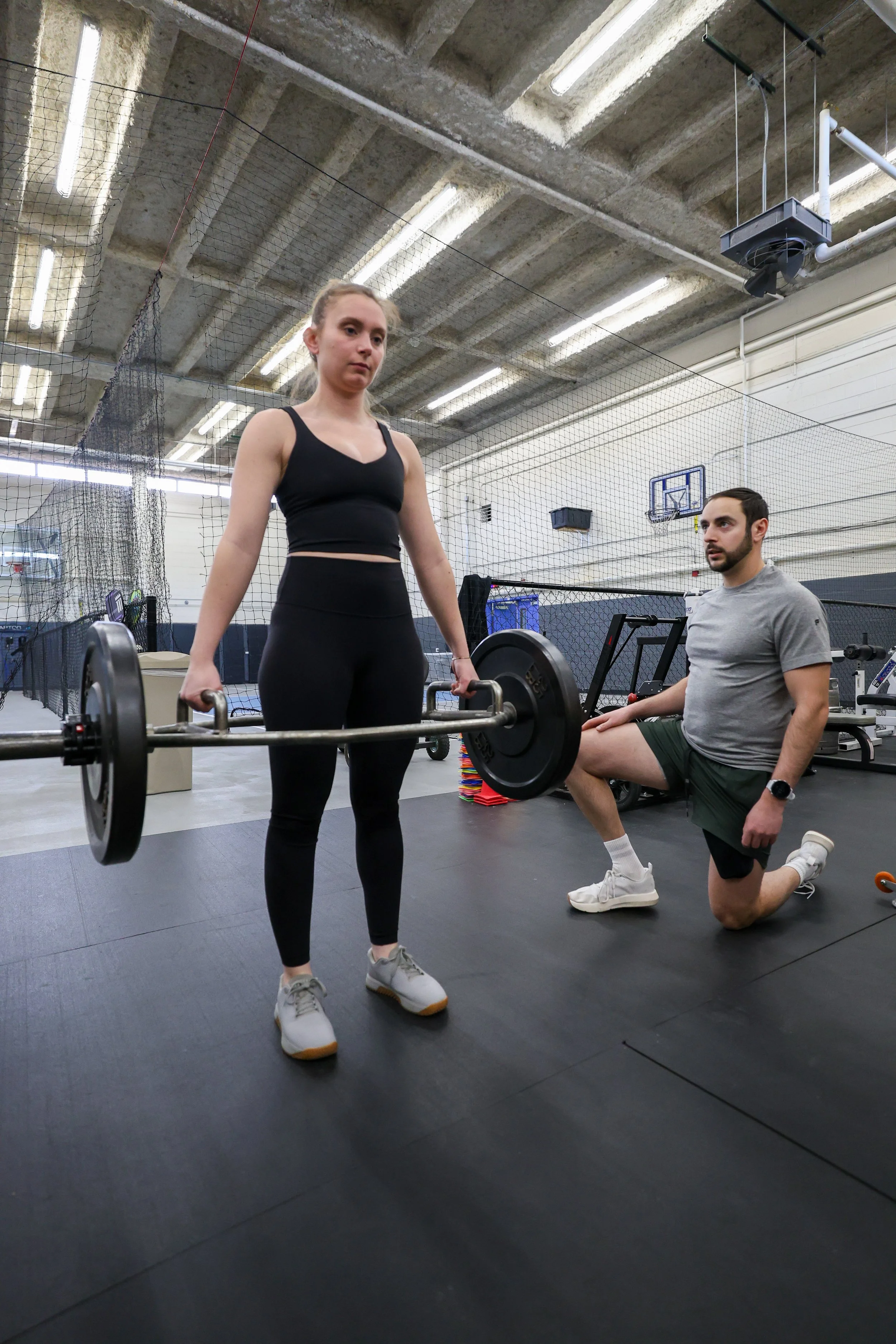 client performing a trap bar deadlift with coach guidance