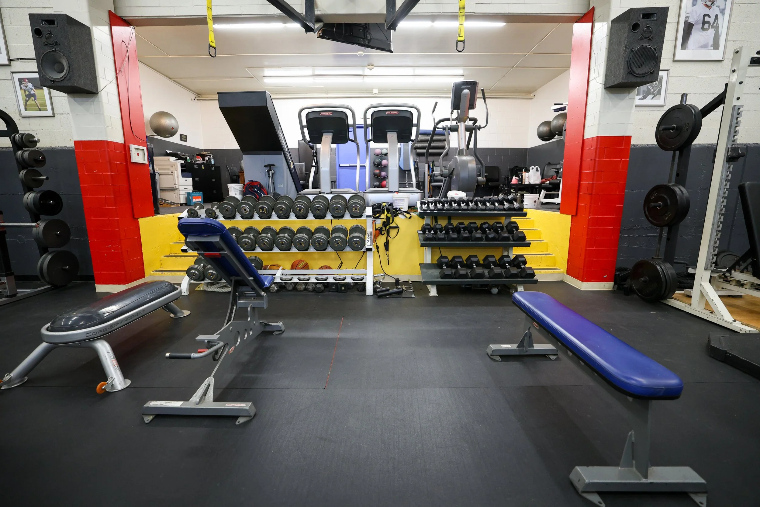 gym space showing various pieces of equipment including benches, dumbbells, and treadmills