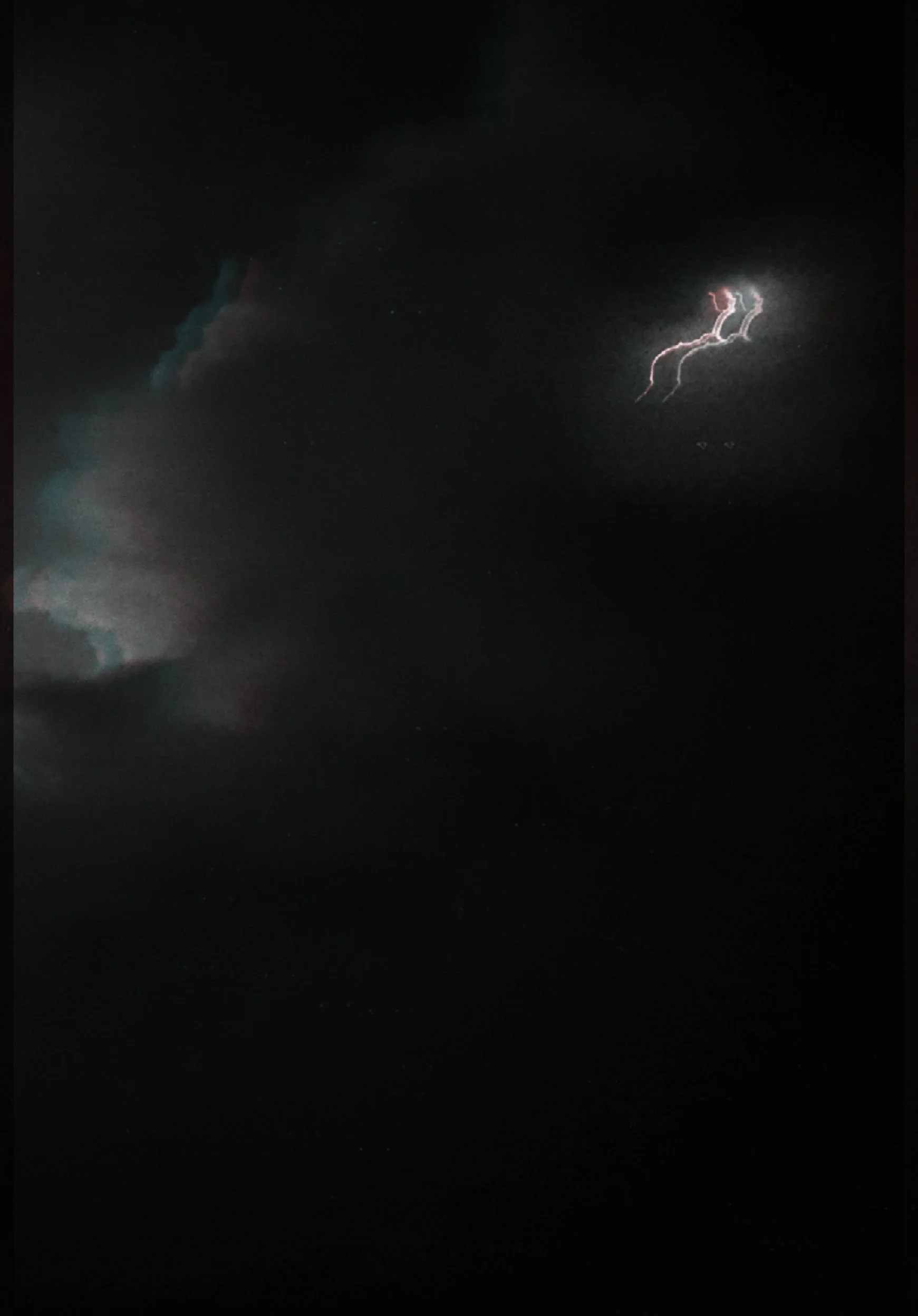 A dramatic nighttime photograph showing a faint double lightning bolt cutting through dark, heavy storm clouds, edited with an atmospheric, low-exposure grain filter.