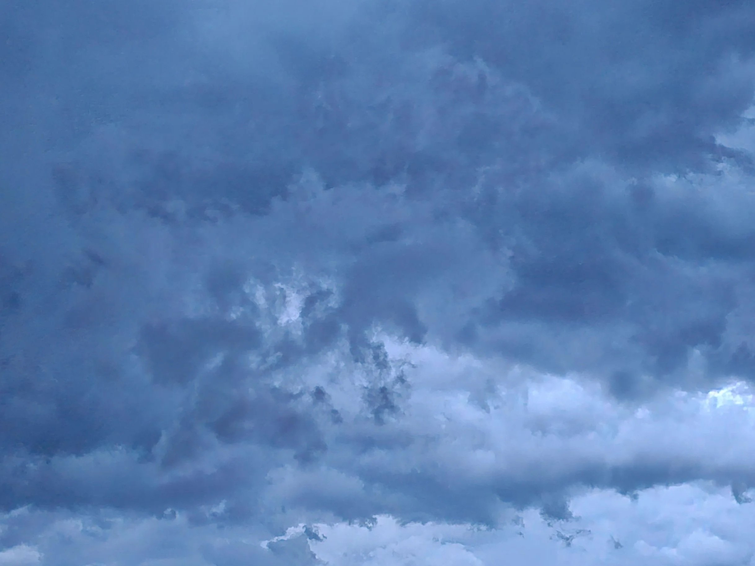 An overcast sky completely filled with dense, textured storm clouds in monochrome shades of slate blue.