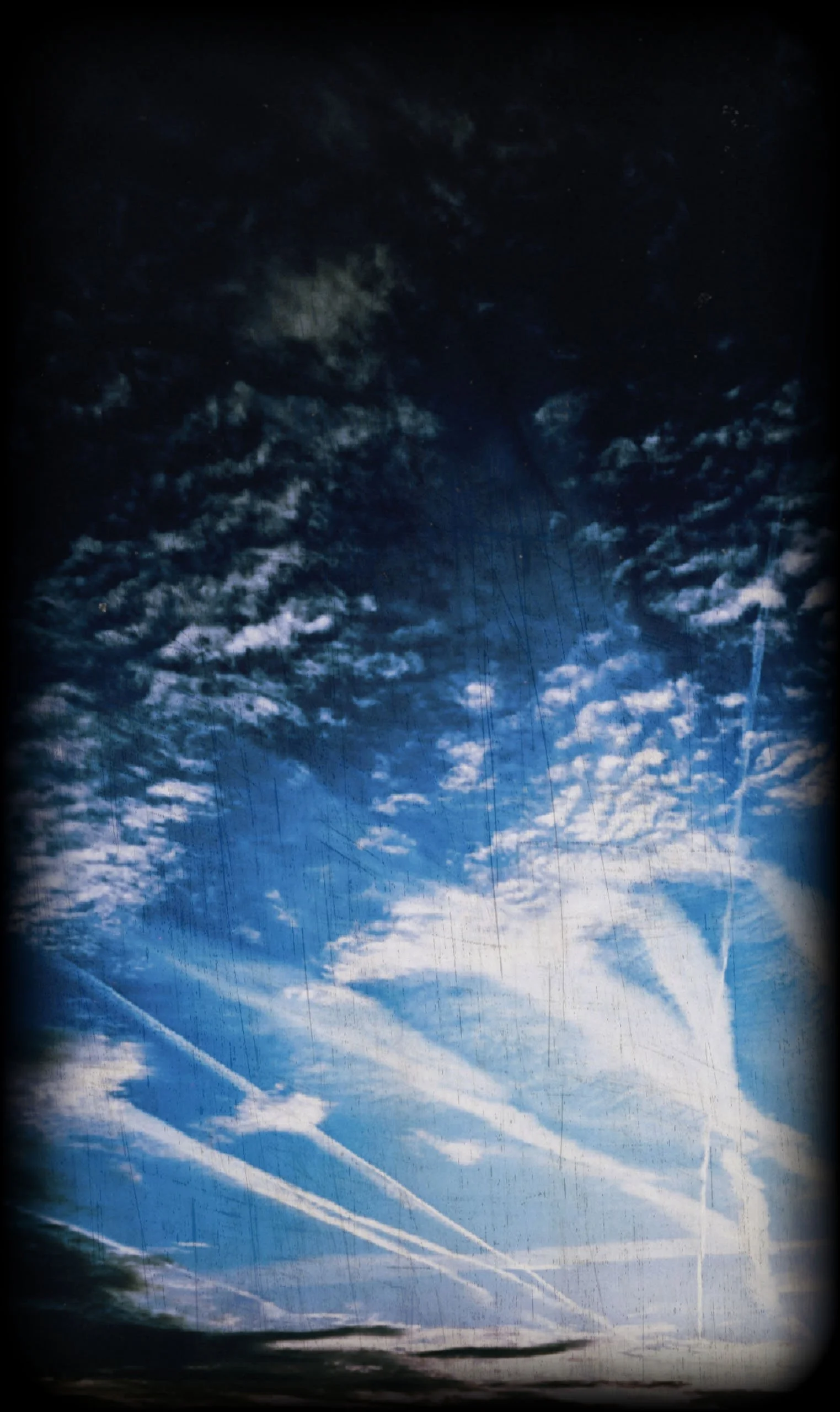 An edited photograph of jet trails streaking across a bright blue sky filled with clouds, styled with a vignette and heavy vintage film textures, giving it a scratched, analog aesthetic.