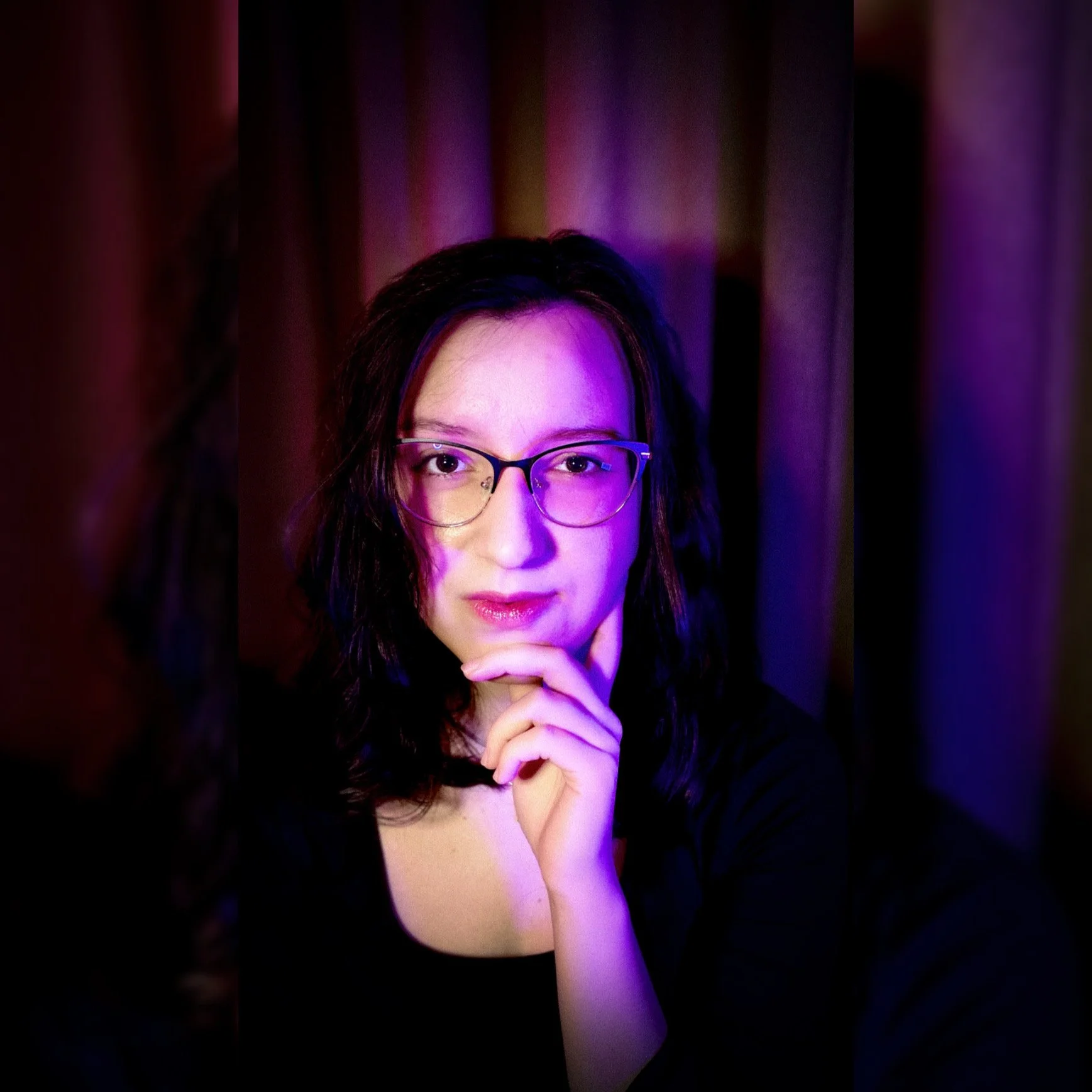 Atmospheric portrait of artist sandra spirou, illuminated by moody bordeaux and deep purple lighting, creating a mysterious and artistic vibe.