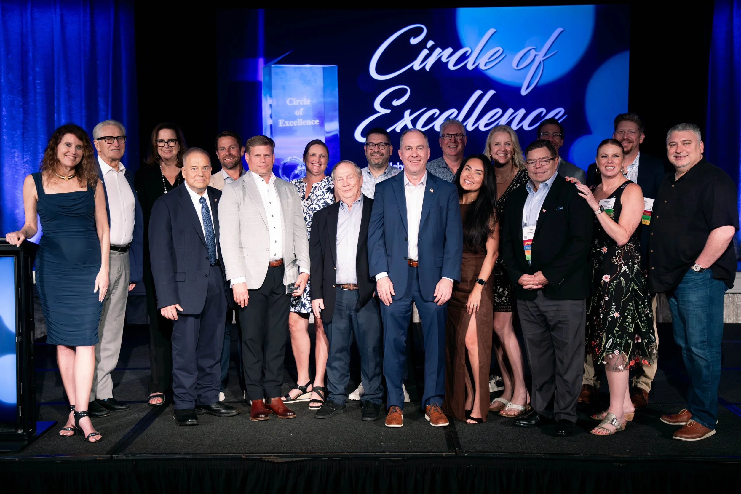 Group of people standing on stage with a backdrop reading 'Circle of Excellence'.