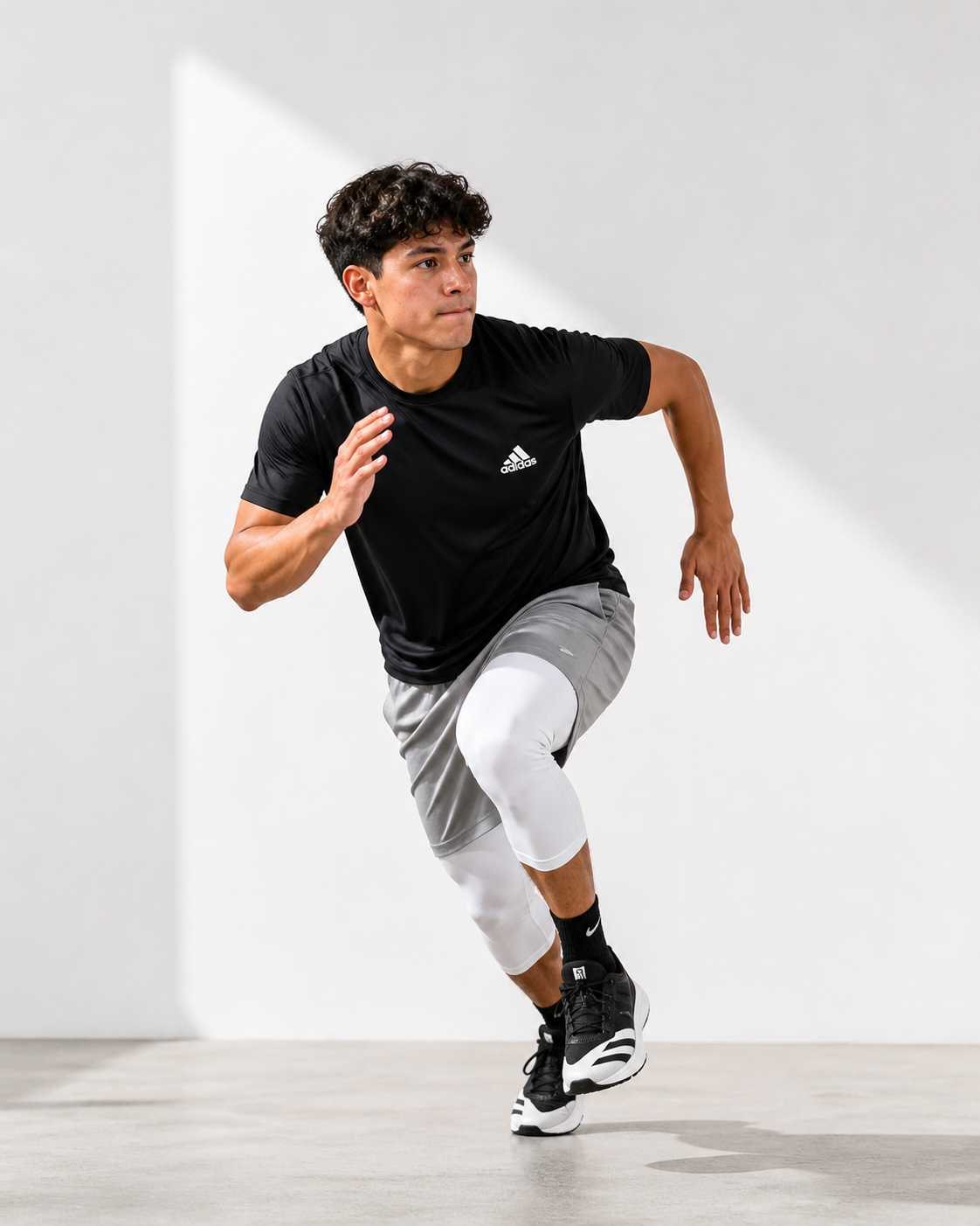 A man in athletic clothing running indoors on a grey surface with a white background.