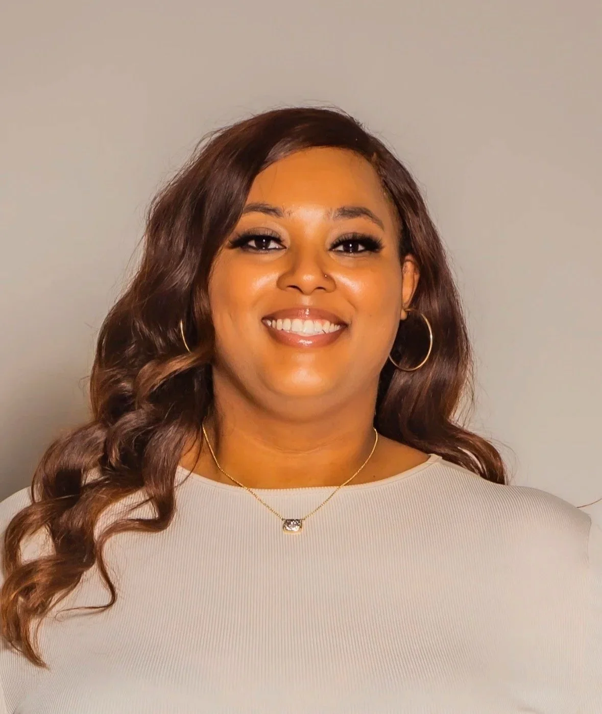 Autumn of Huntsville Behavior Associates with long wavy brown hair, wearing hoop earrings, a pendant necklace, and beige top.