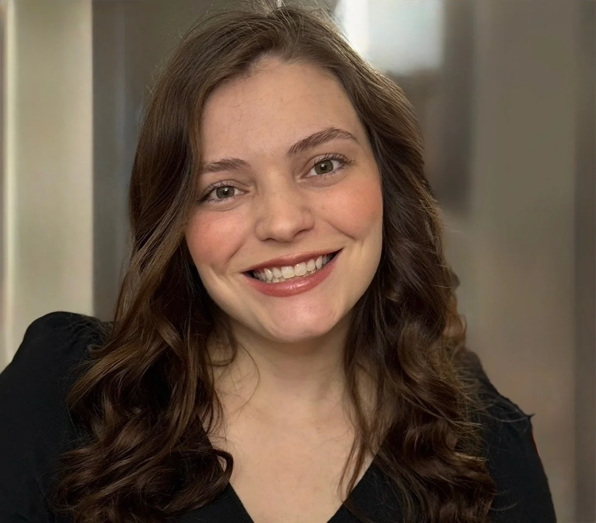 Kailey of Huntsville Behavior Associates smiling with wavy brown hair and wearing a black top in an indoor setting.