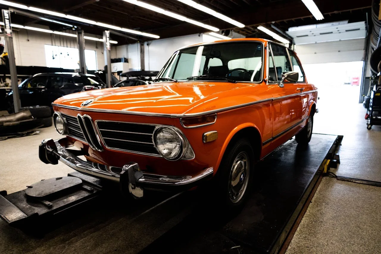 An orange classic BMW car inside a garage or showroom.