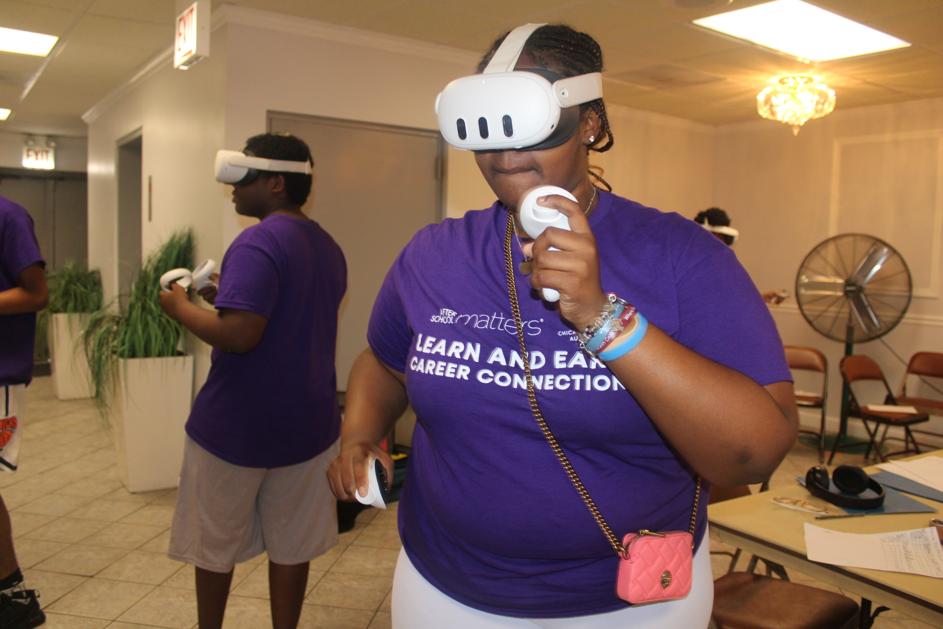 Group in purple shirts using VR headsets and controllers indoors.