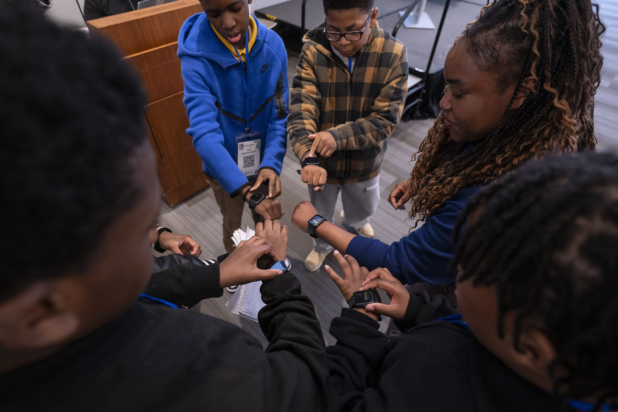 Students and teacher standing in a circle displaying smartwatches.