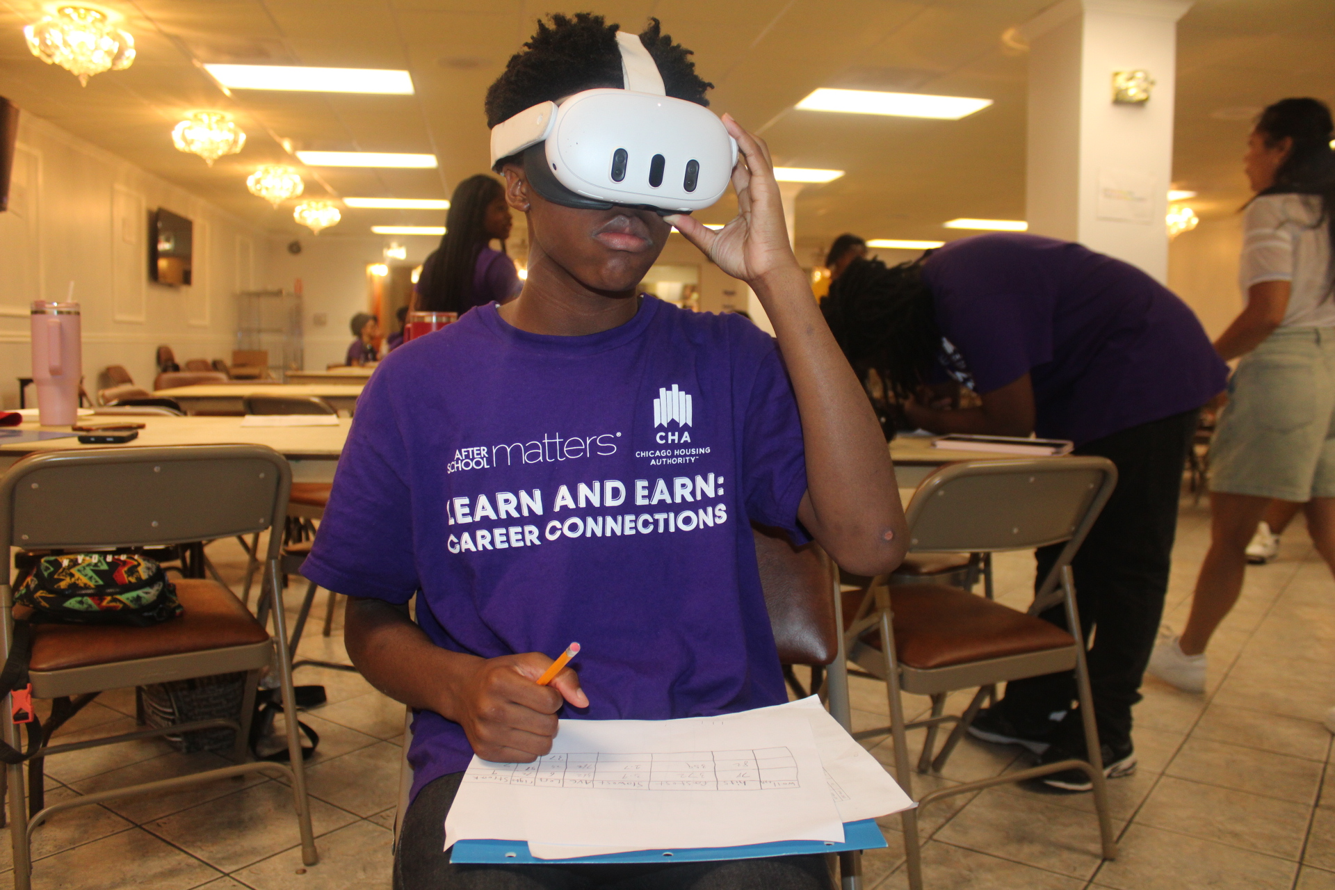 Person in VR headset completing a worksheet in a bright learning space.